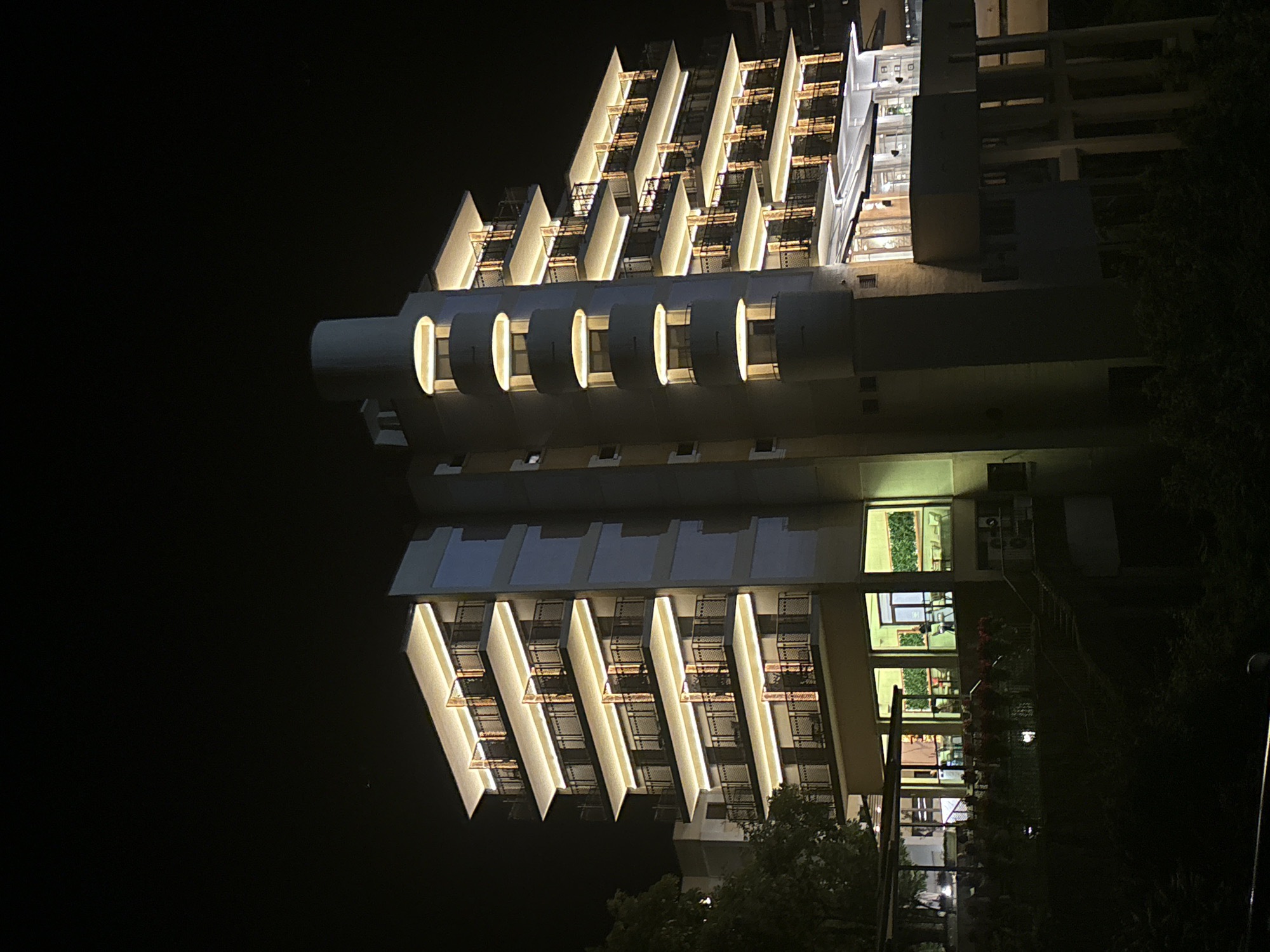 Nighttime urban scene with illuminated buildings and luxury cars