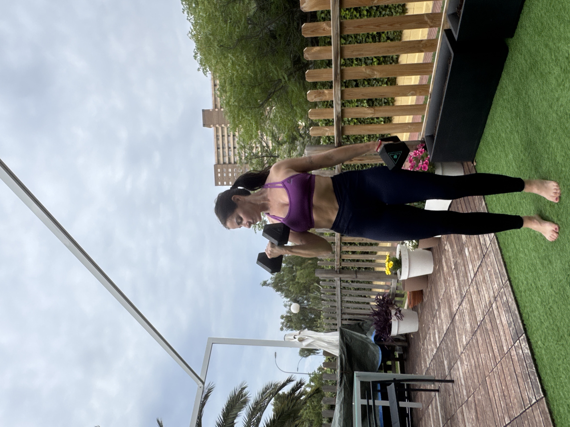 Woman exercises with dumbbells on patio in Alicante