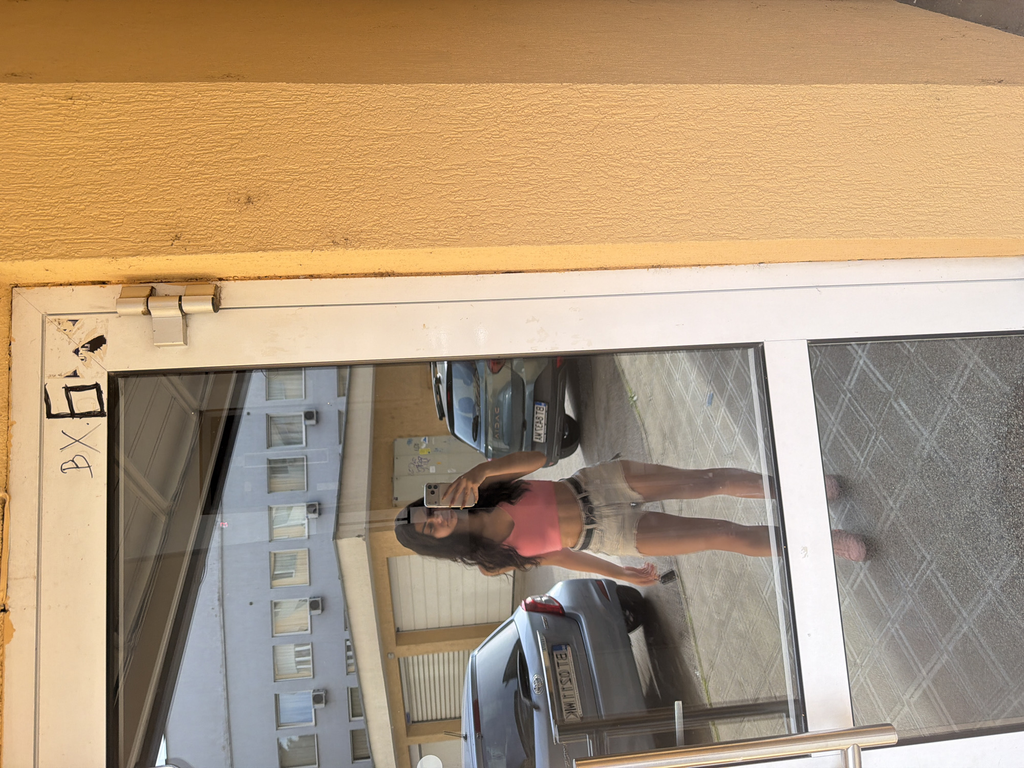 Woman takes mirror selfie at glass door in Veliko Tarnovo