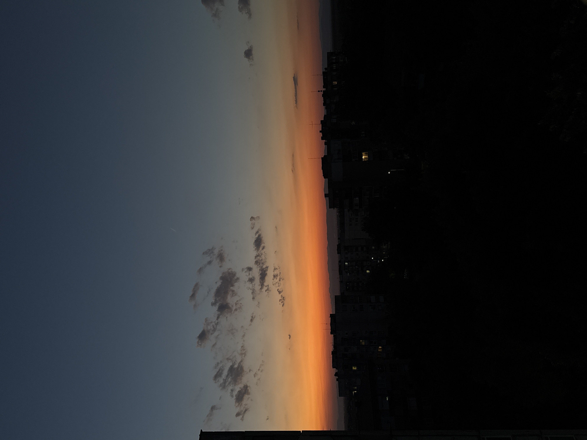 City skyline at golden hour, sky fading blue to orange