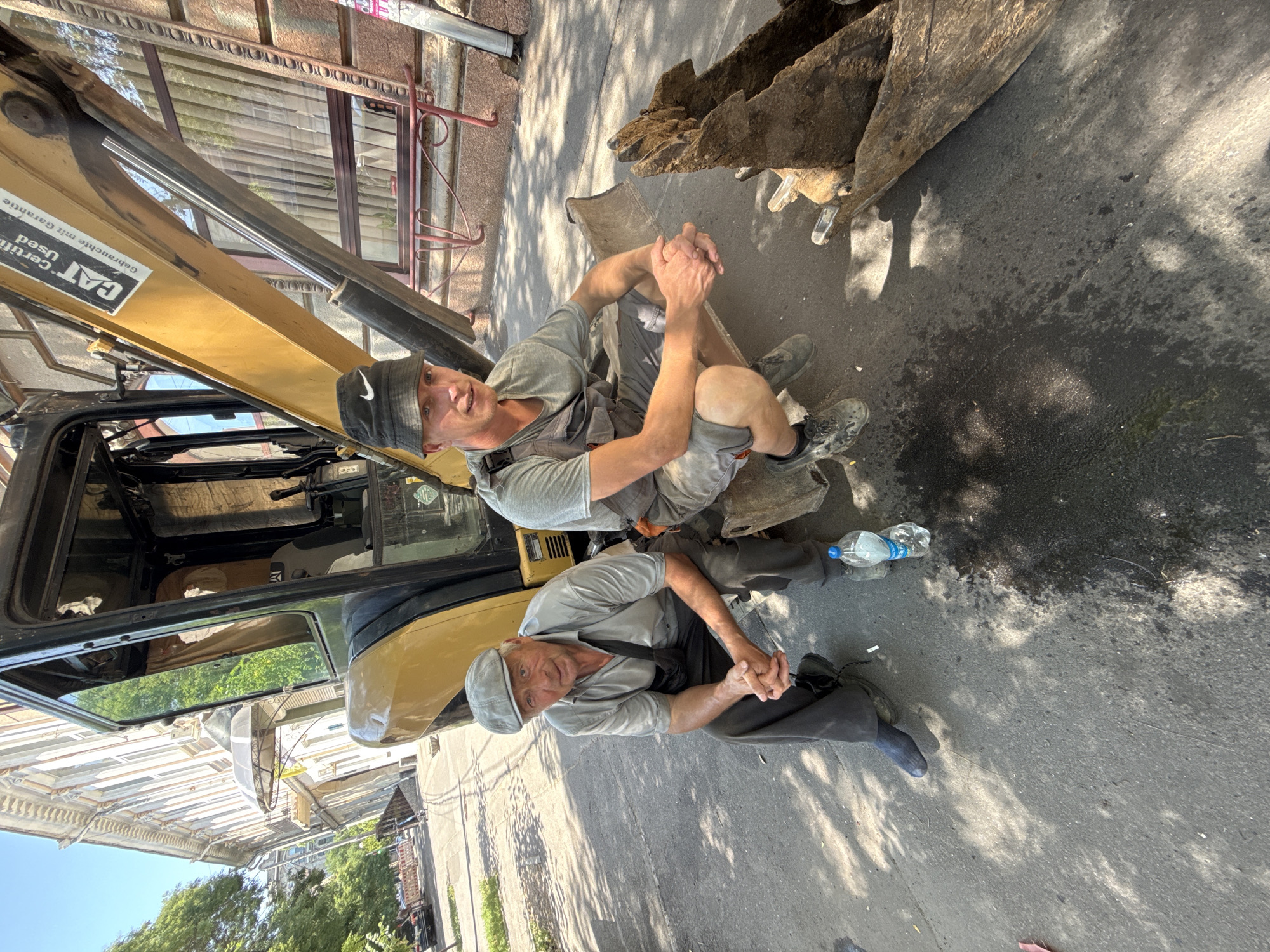 Construction crew works and rests beside a yellow excavator