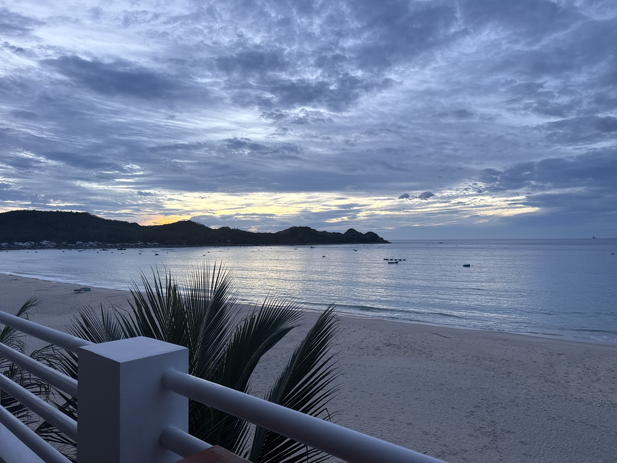 Dusk closes in over a cloudy beachfront shoreline.