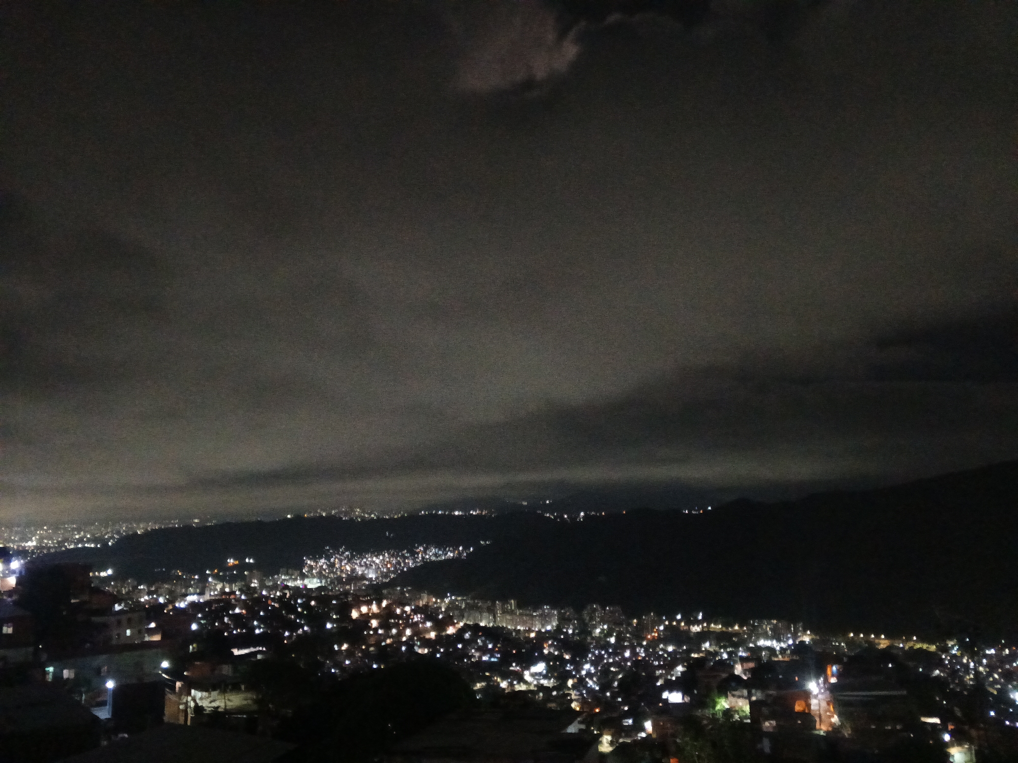 Nighttime observations capture illuminated Caracas under cloudy moonlit sky
