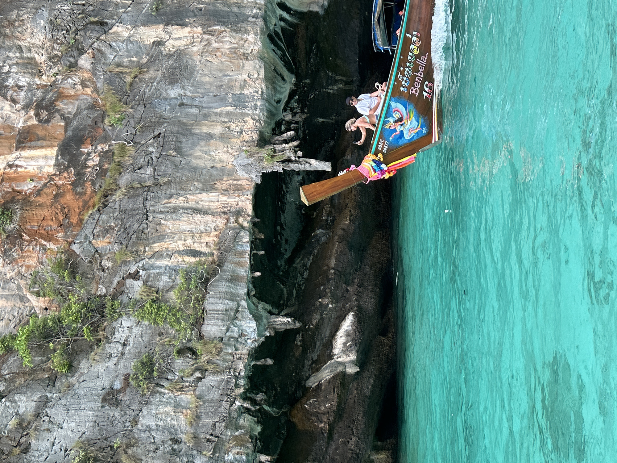 Longtail boat cruising past cliffs and islands at Haad Yao