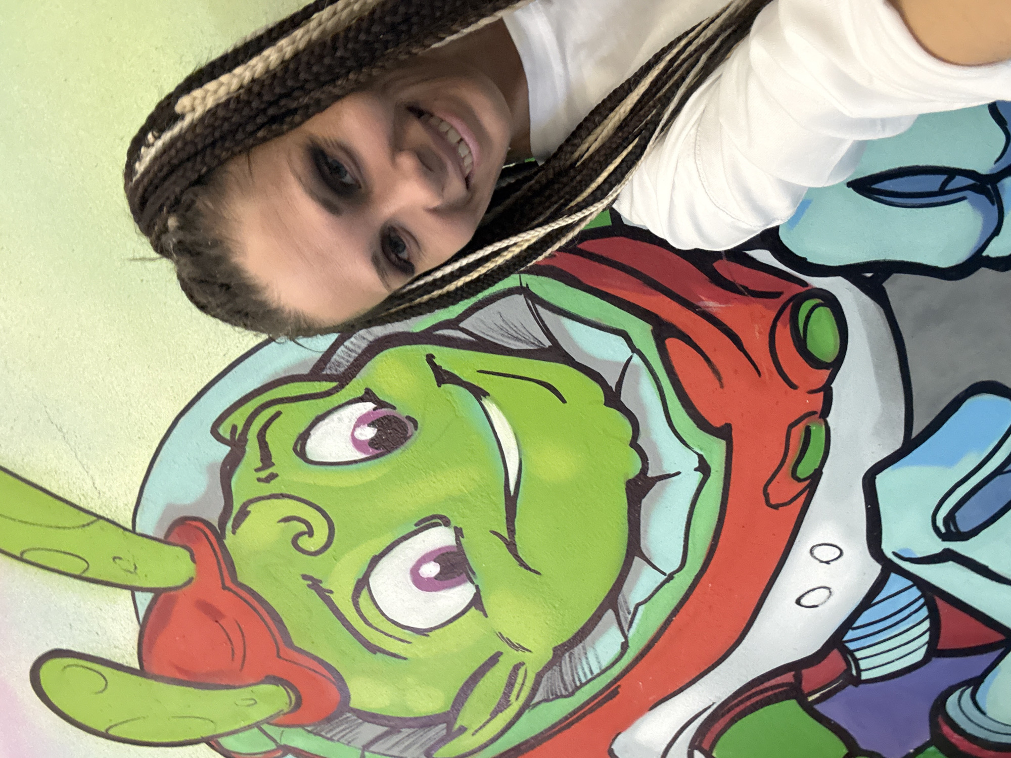 Person poses with alien mural artwork