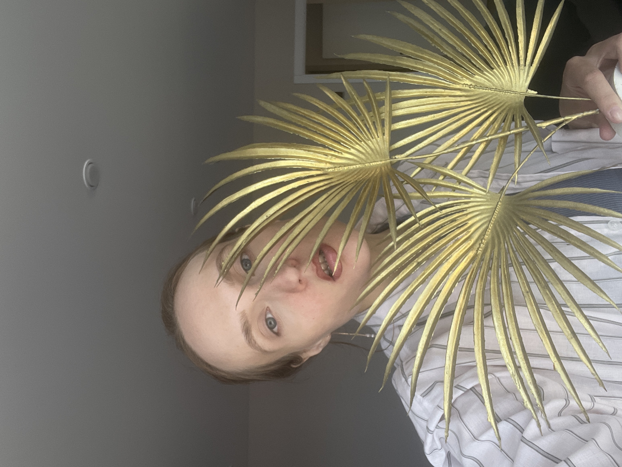 Person poses with golden palm fronds in Sepych, Russia