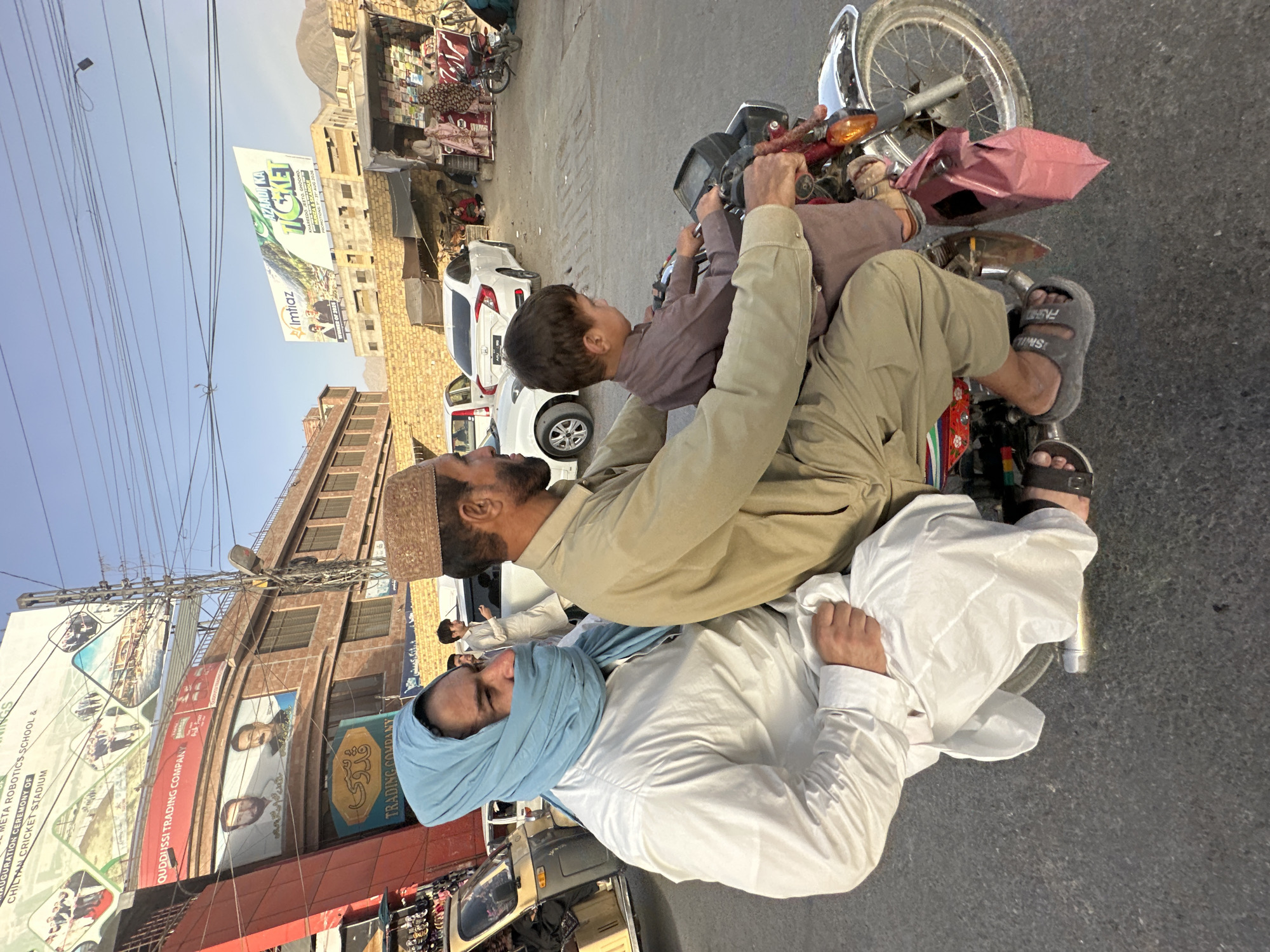 Quetta street market buzzes with traffic, textiles, and daily life.