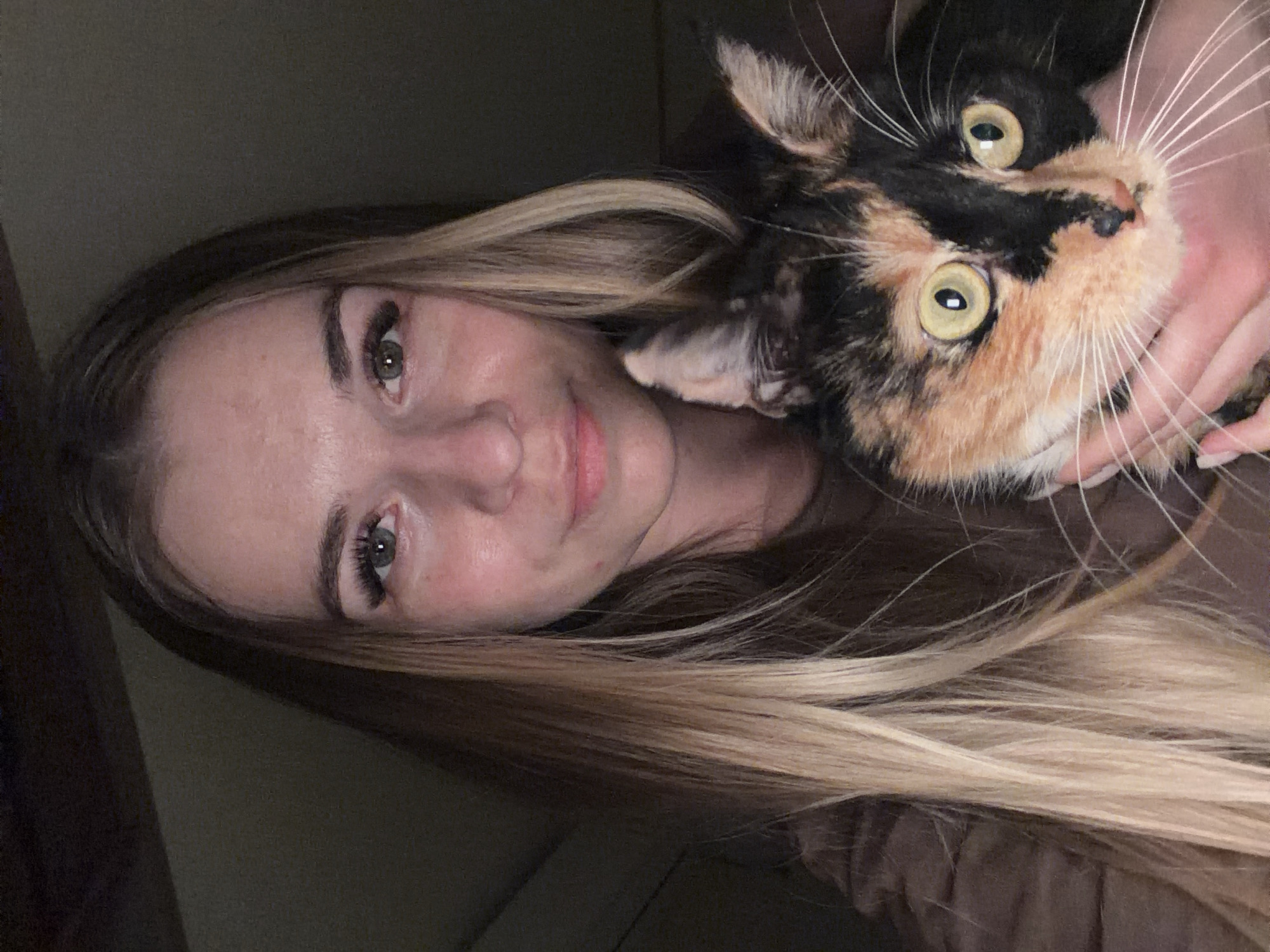 Woman holds calico cat in intimate moment