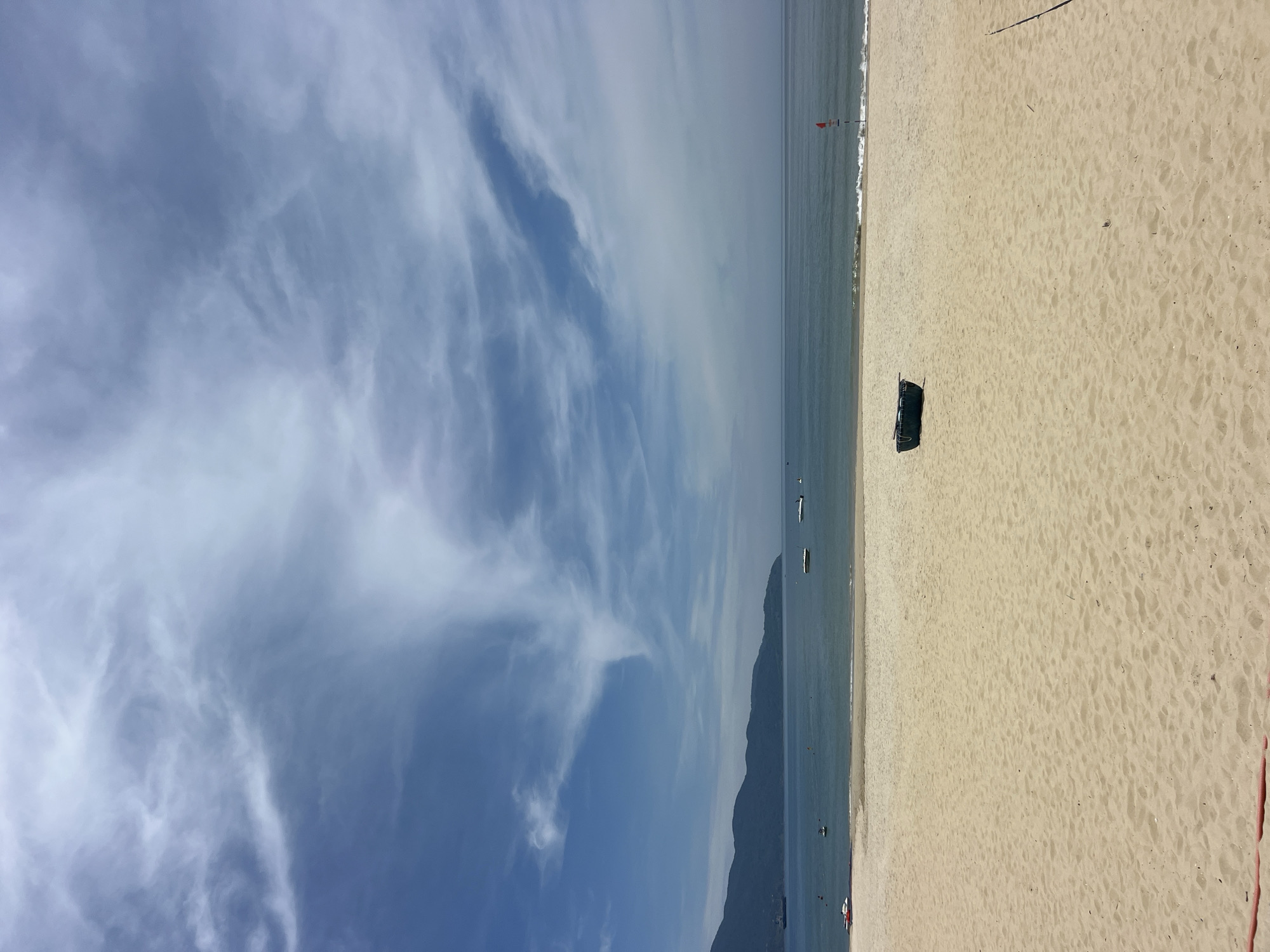 Sunny beach day with volleyball net, umbrellas, and coastal details