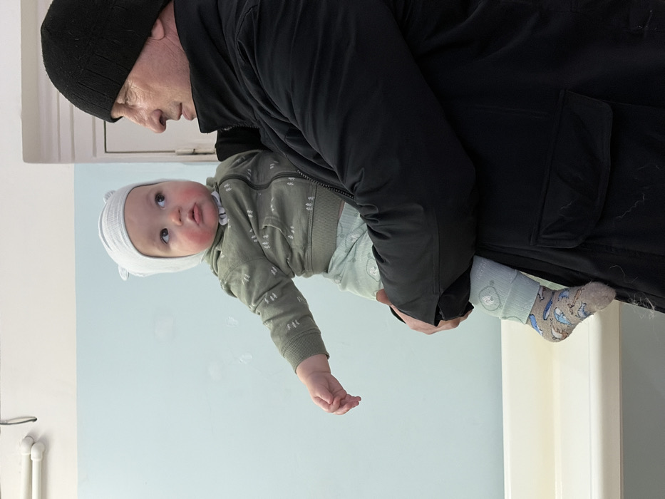 Adult holds baby indoors during Russian winter morning
