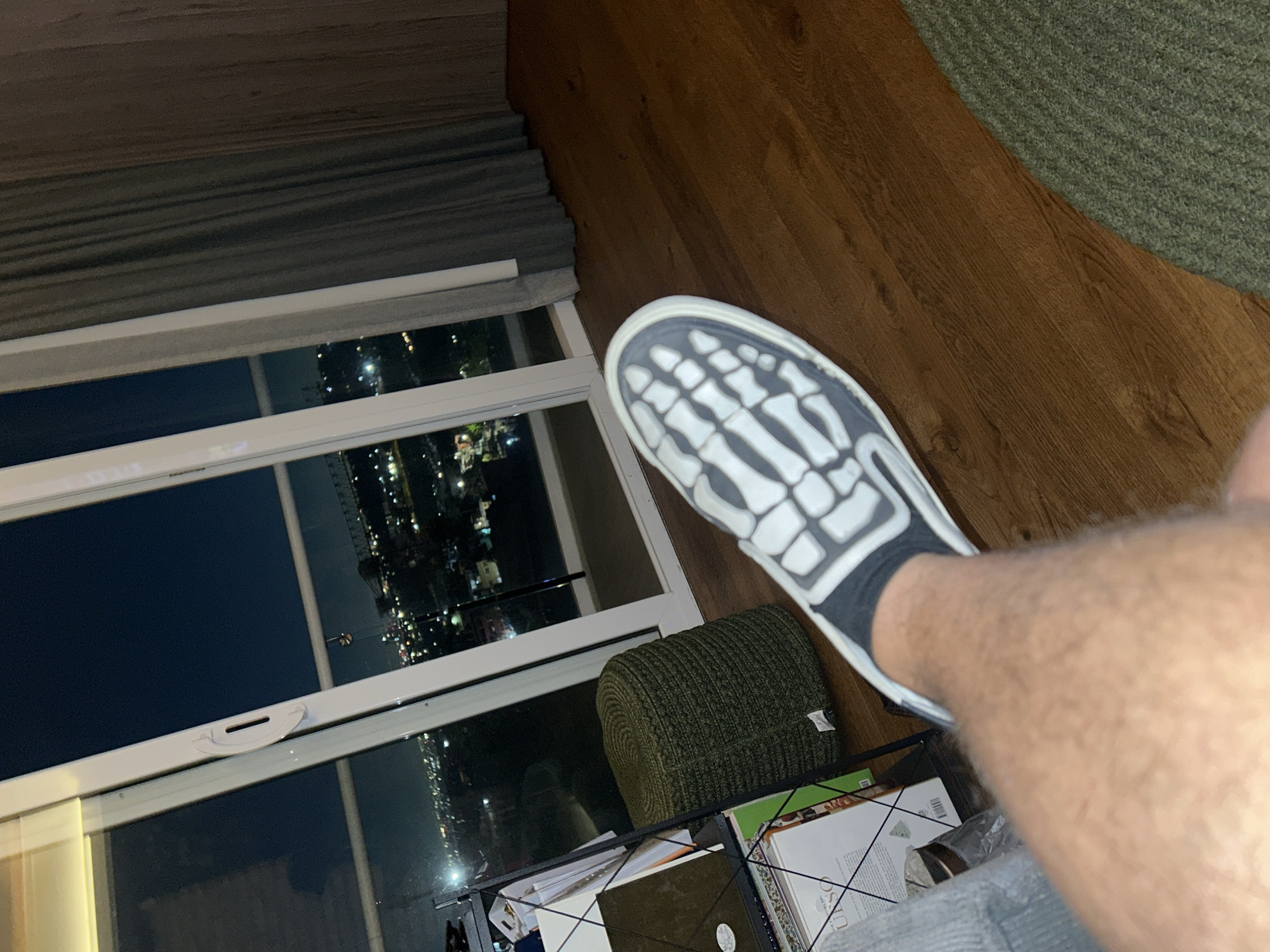 Person photographed by window in Huixquilucan wearing skeleton-print shoes