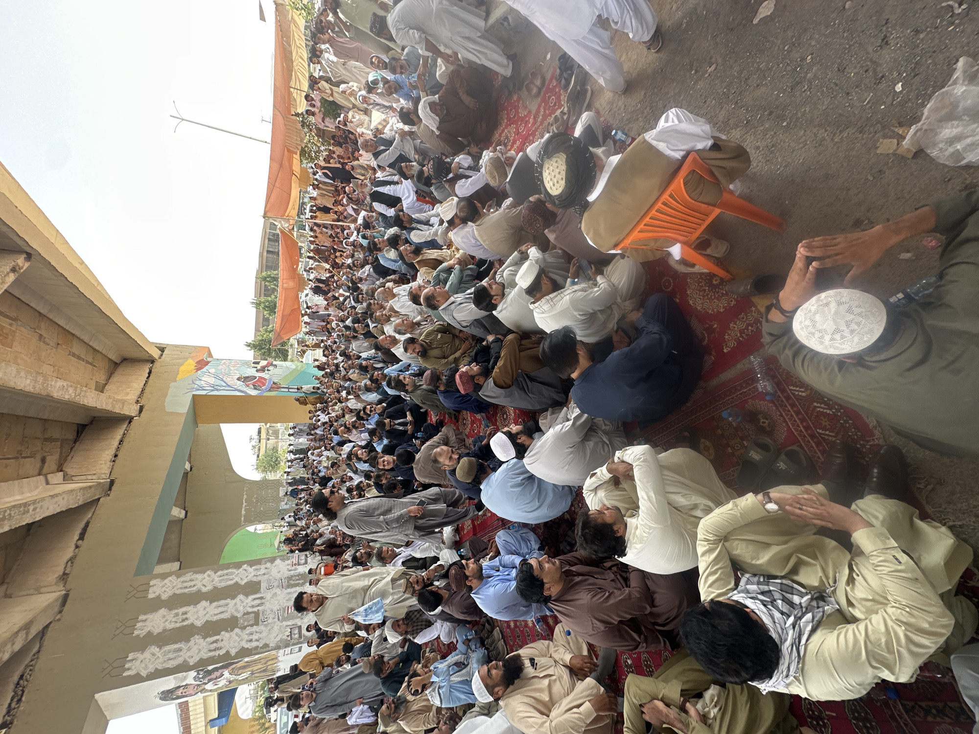 Outdoor gathering under overpass, address to seated crowd