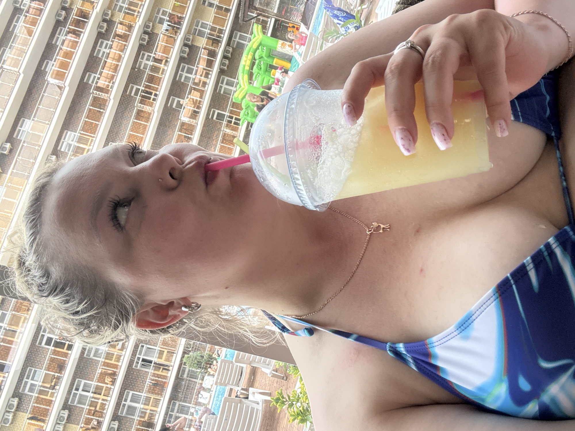 Woman enjoys poolside drink at indoor facility