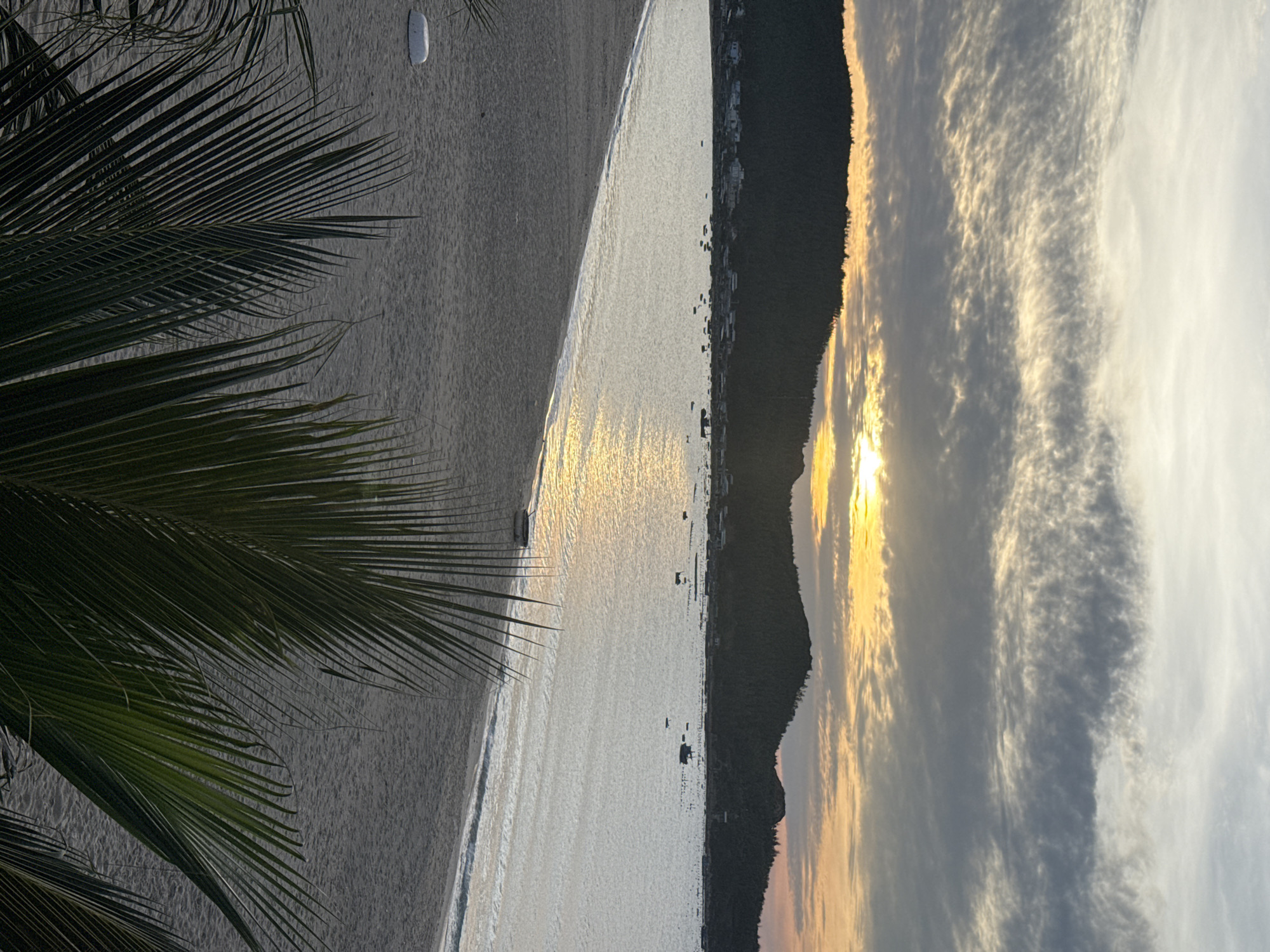 Dusk beach scene with golden sunset over calm water