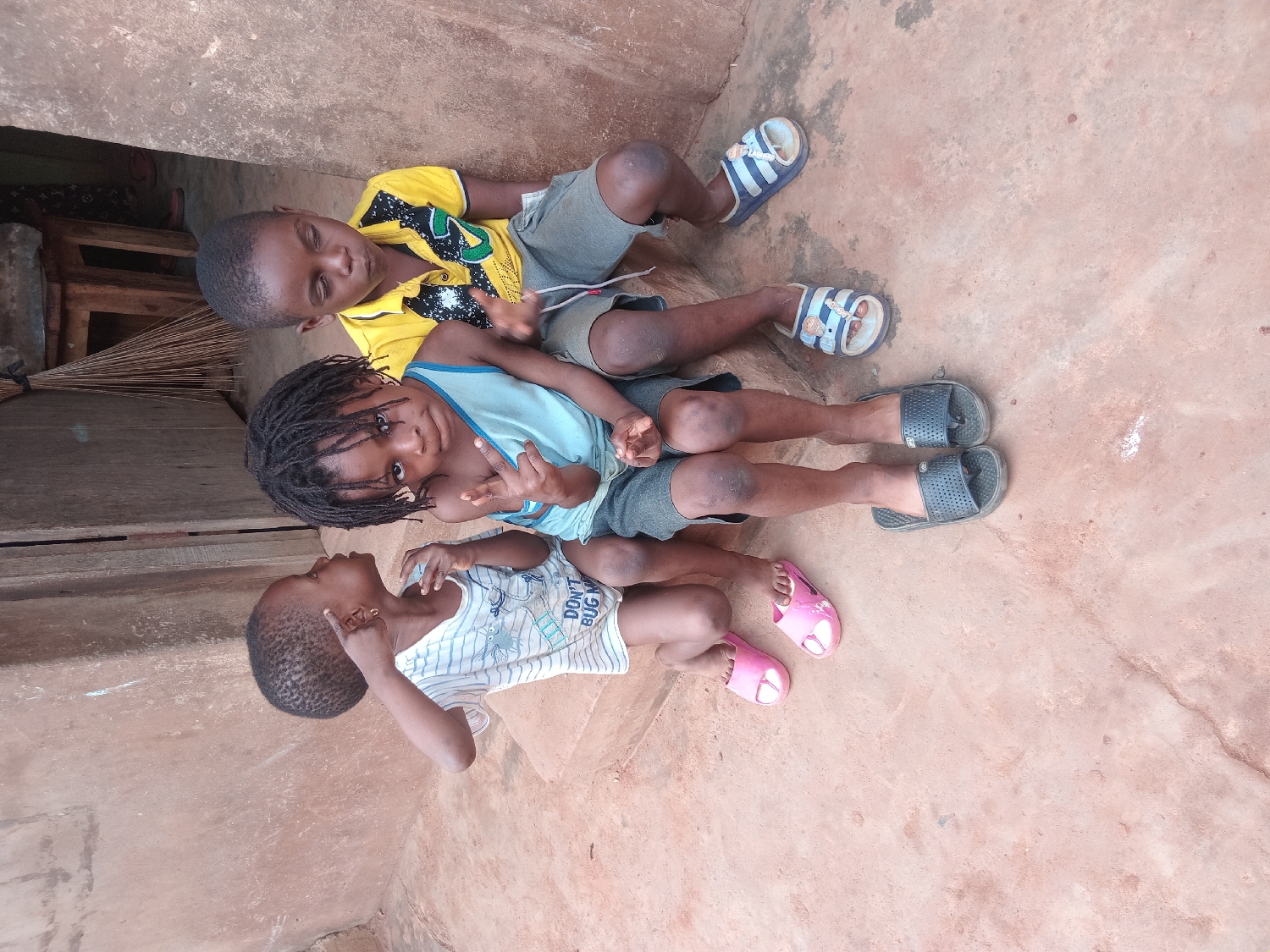 Children rest on ground with scattered shoes in Shagamu