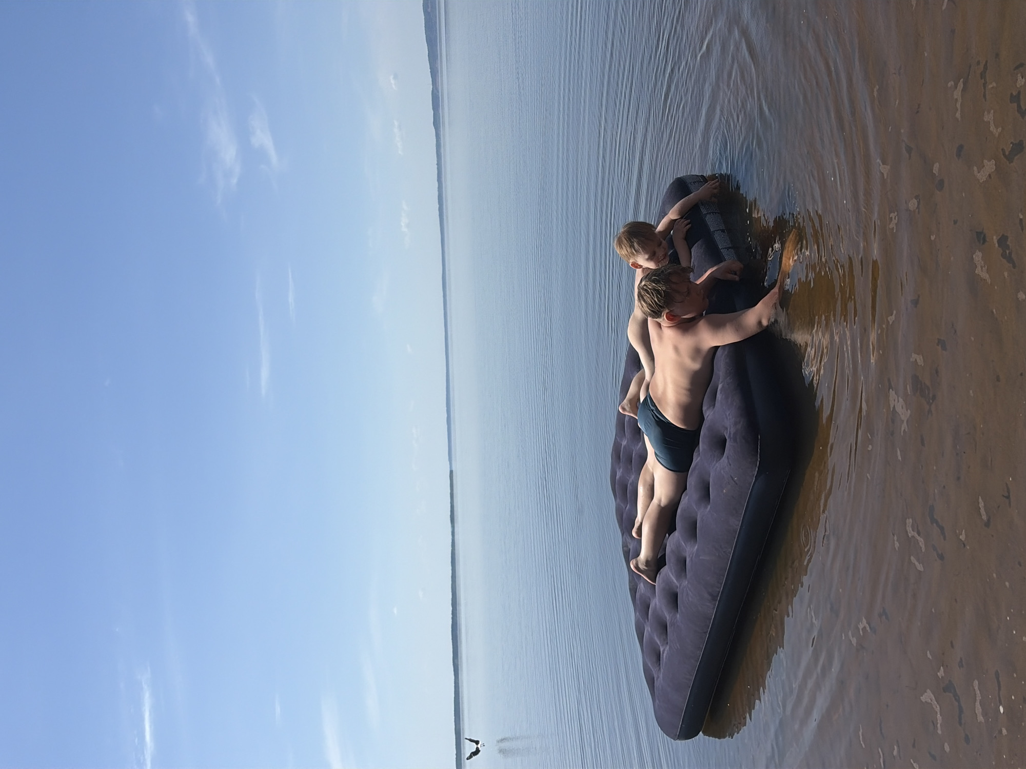 Children play on inflatable mattress in Zabegaevo waters