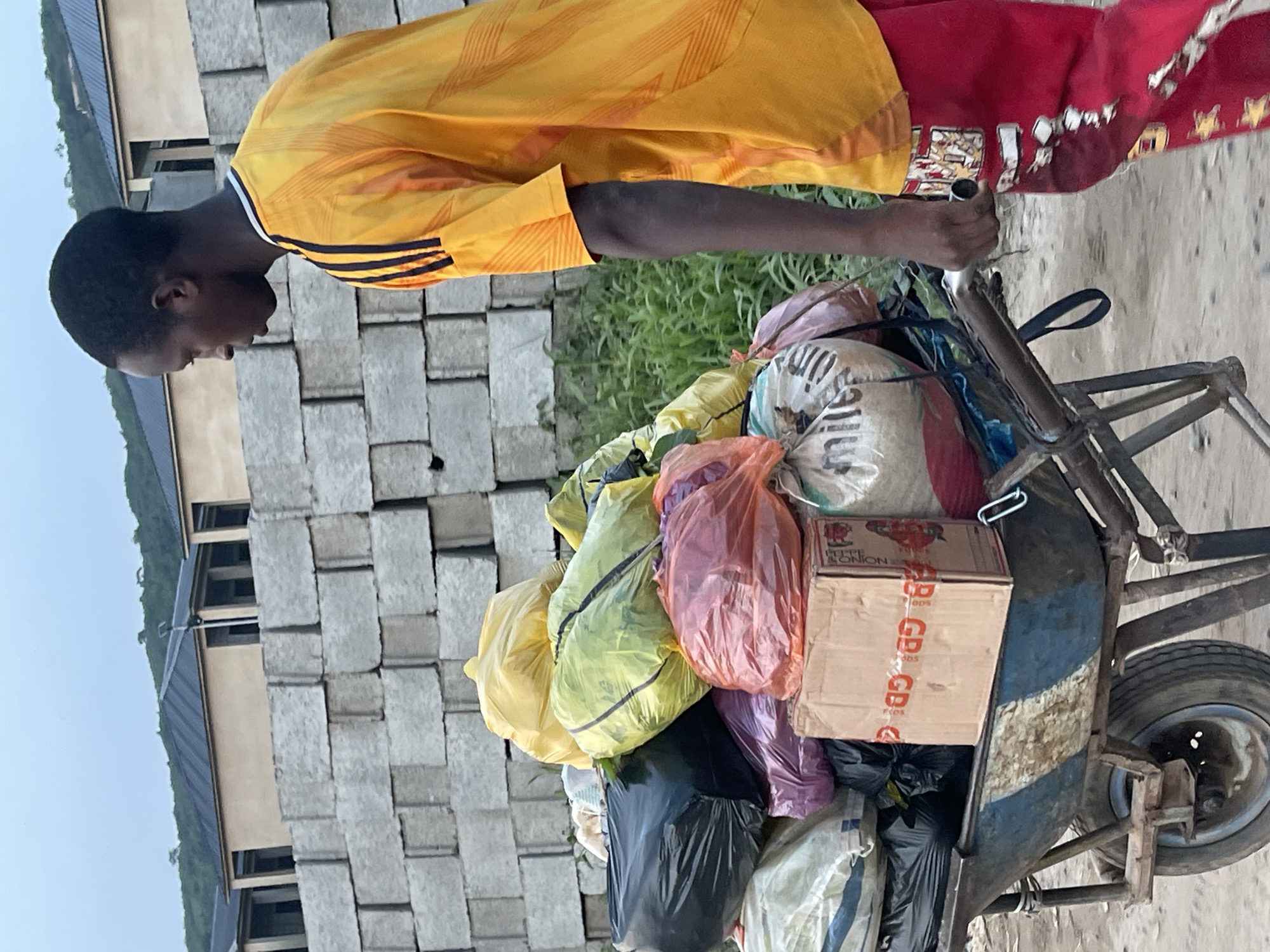 Wheelbarrow loaded with colorful plastic bags moves through Abuja