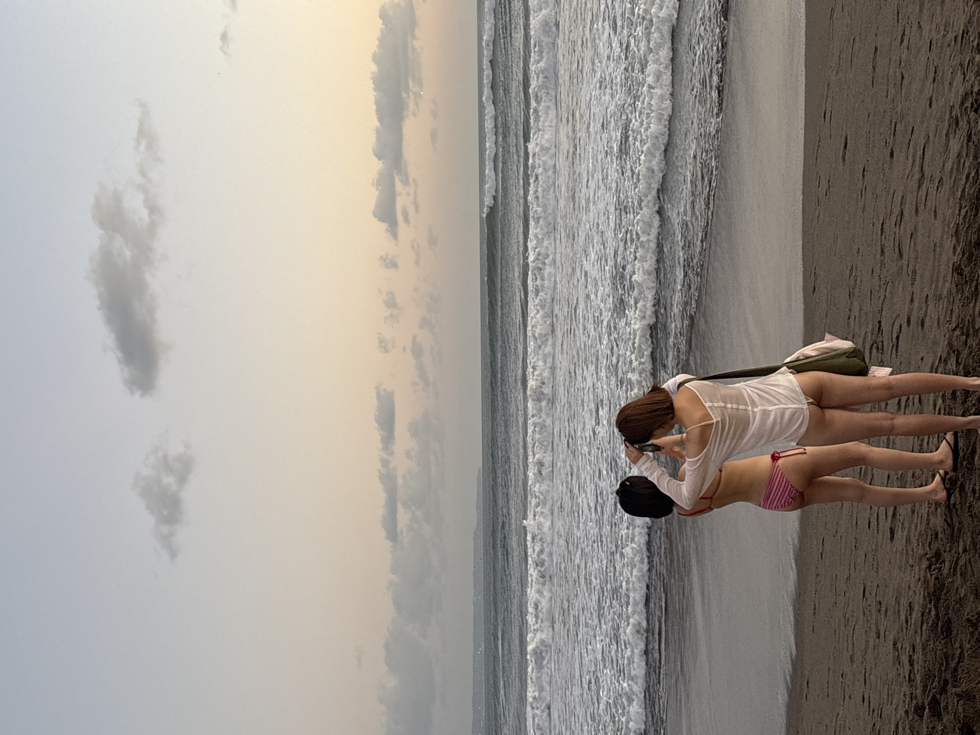 North Kuta beach at dusk, people, a dog, and soft pink skies