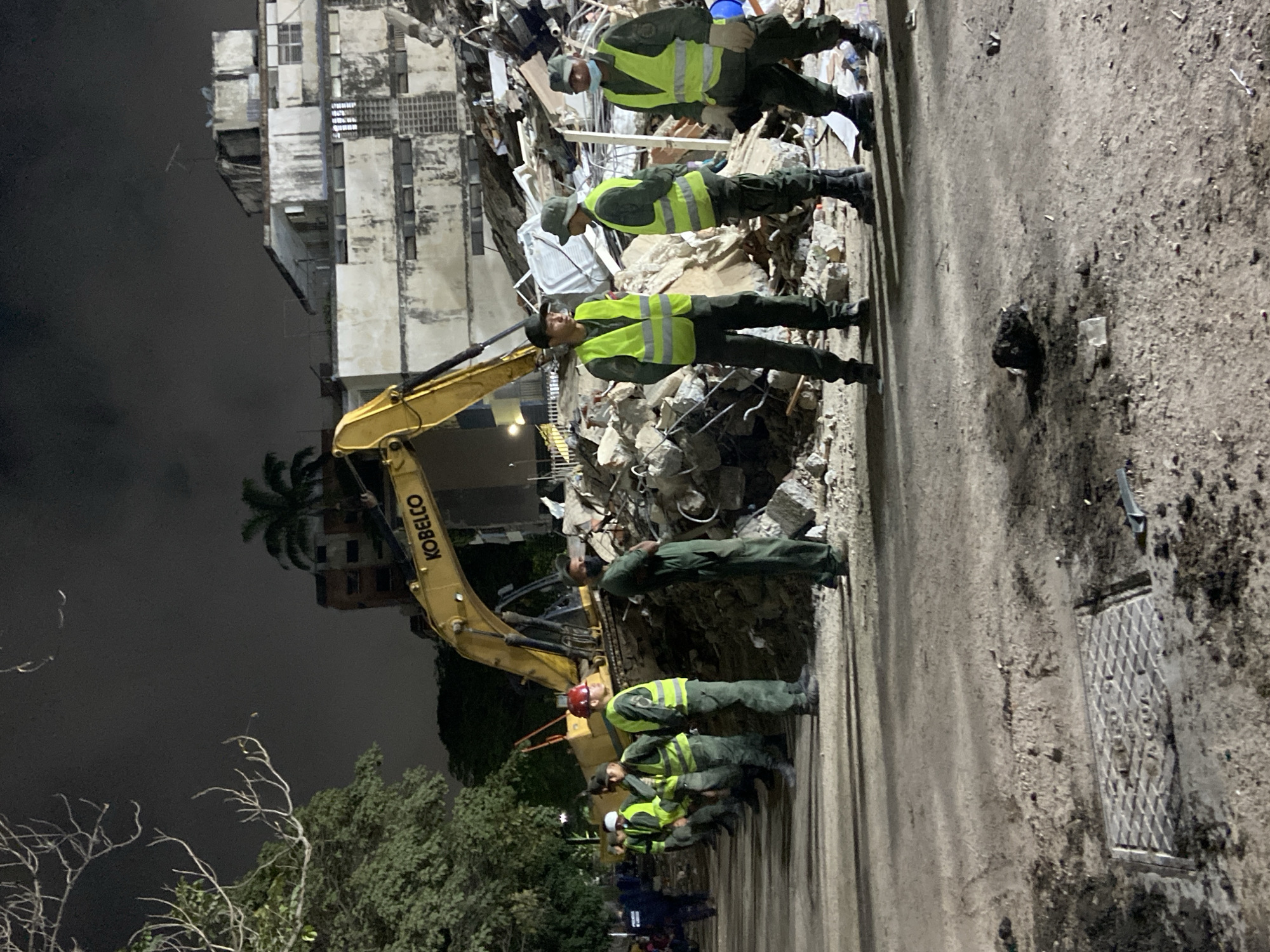 Nighttime building collapse response in Caracas, excavator on site