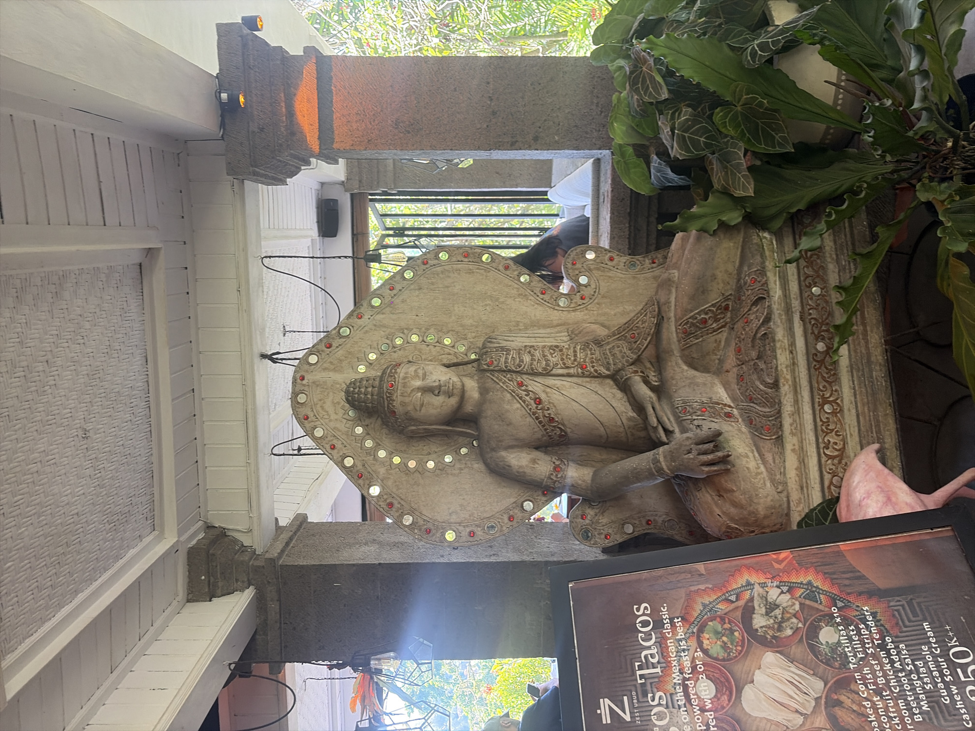 Ornate Buddha statue in a sunlit Ubud courtyard