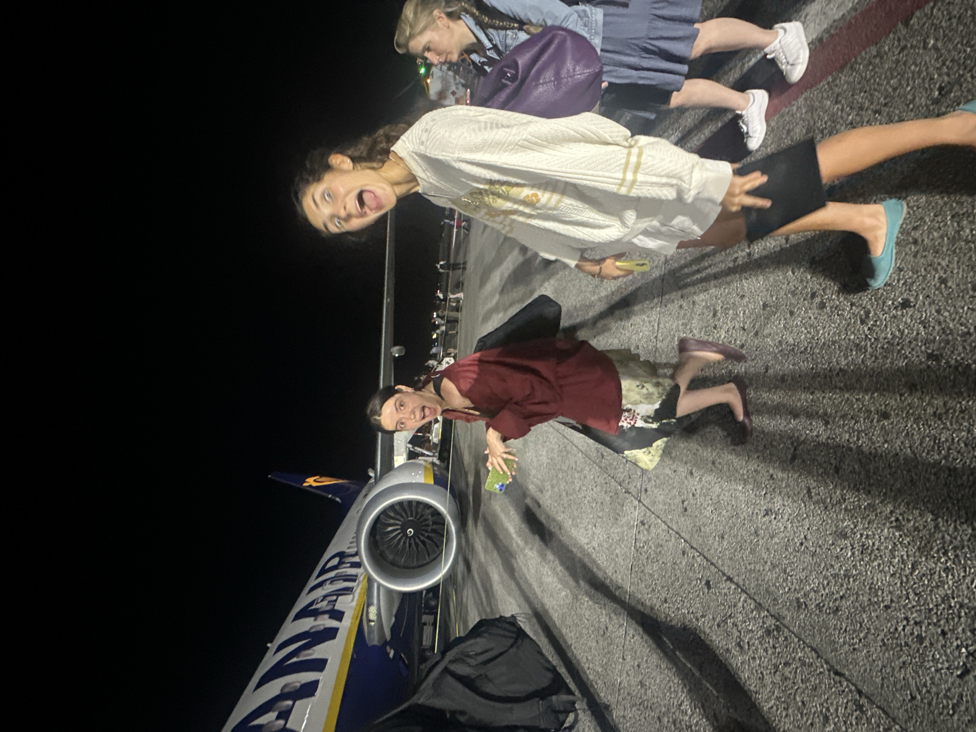 Young women pose playfully on Pisa airport tarmac