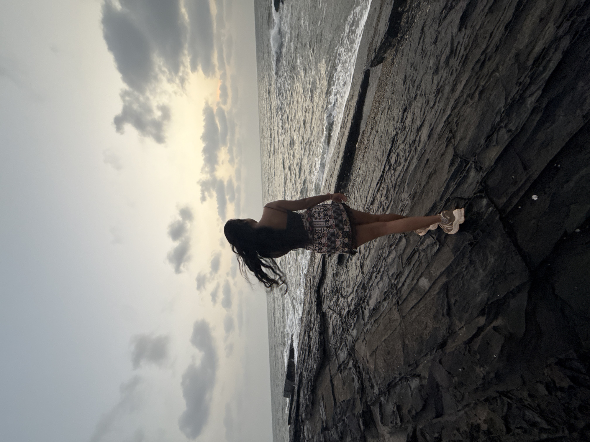 Woman stands on rocky coastline in Calangute, India