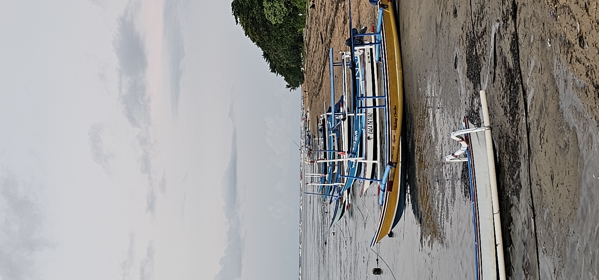 Evening coastal scenes captured in Denpasar featuring traditional boats, visitors