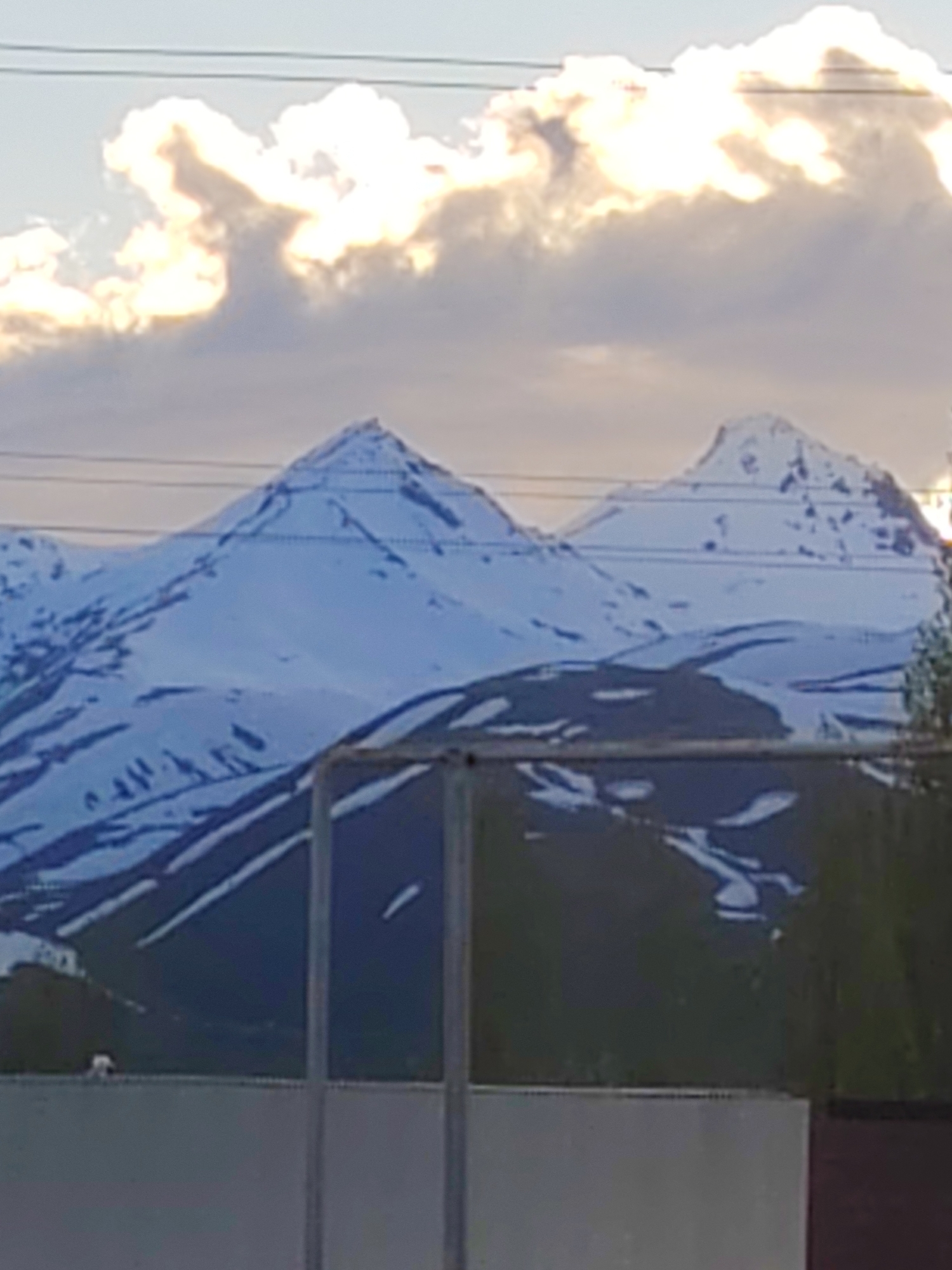 Snow-covered mountain peaks observed under cloudy skies