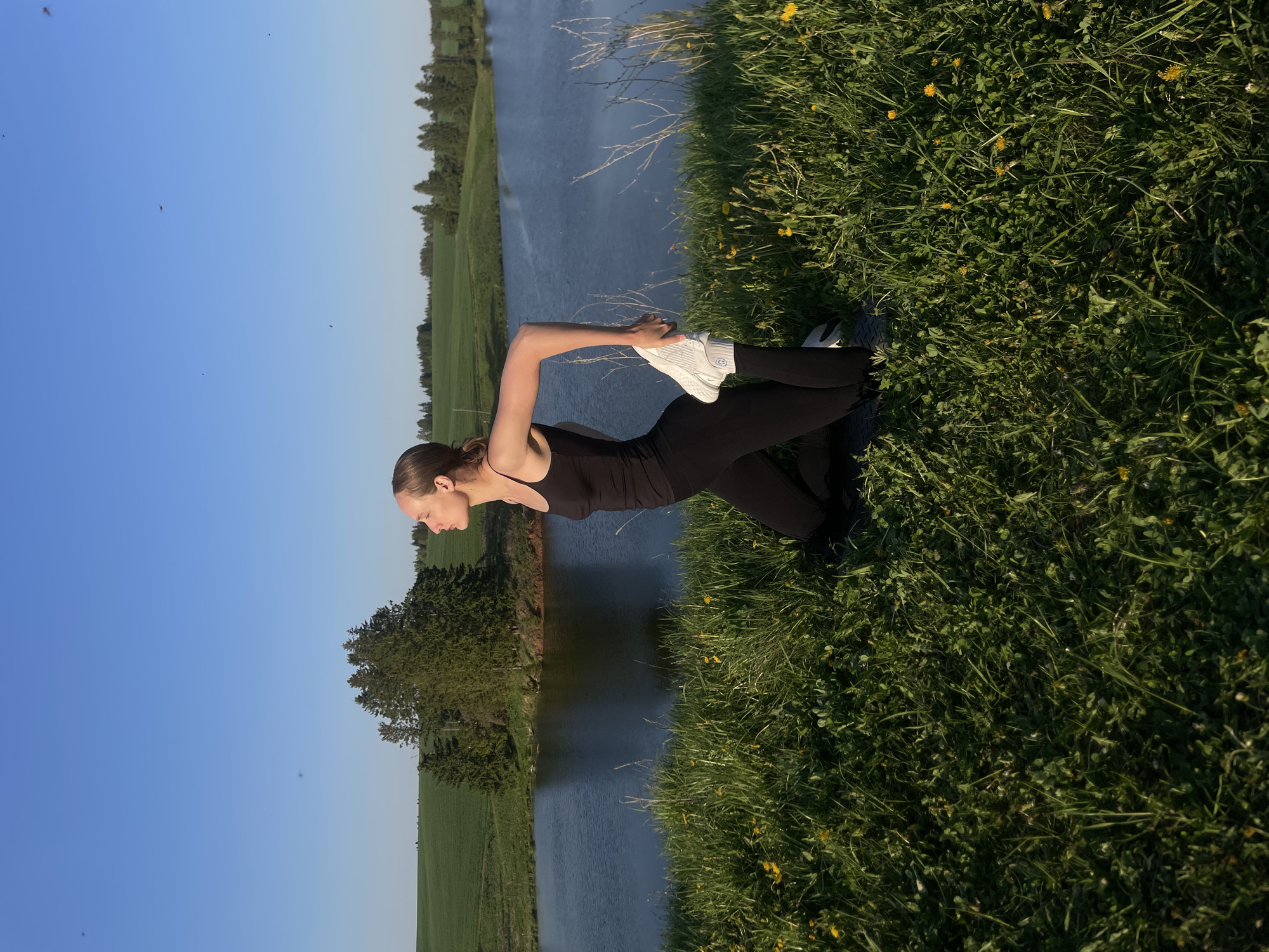 Woman performs outdoor yoga routine by water in Подшивалово