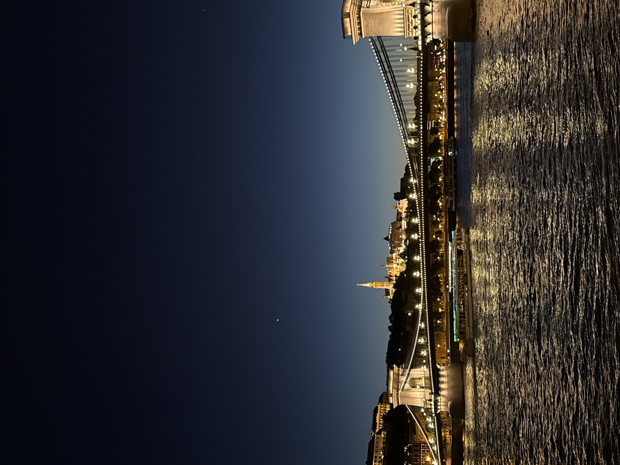 Budapest Chain Bridge illuminated at night, boats passing beneath