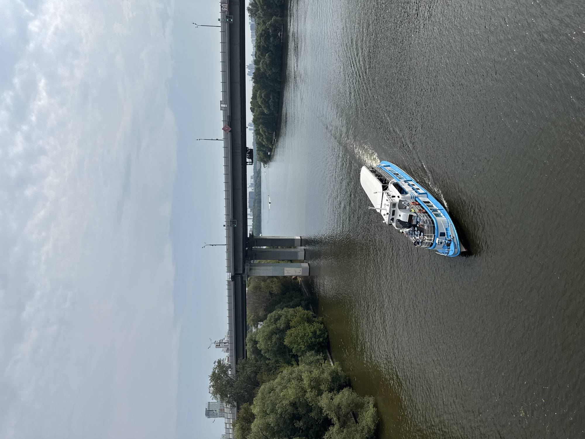 Red arch bridge and passenger ferry on a wide city river