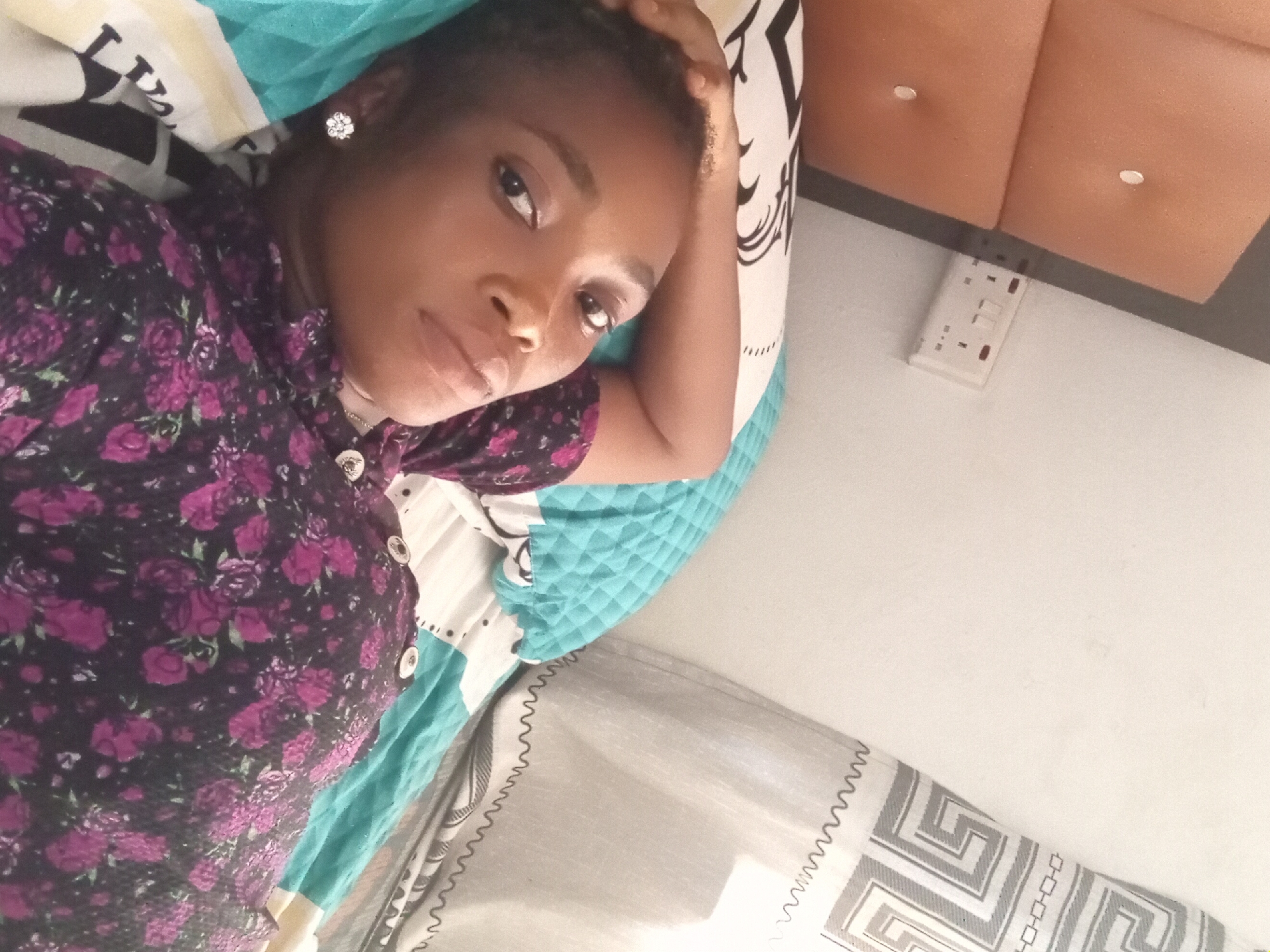 Woman rests on bed in Shagamu, Nigeria afternoon