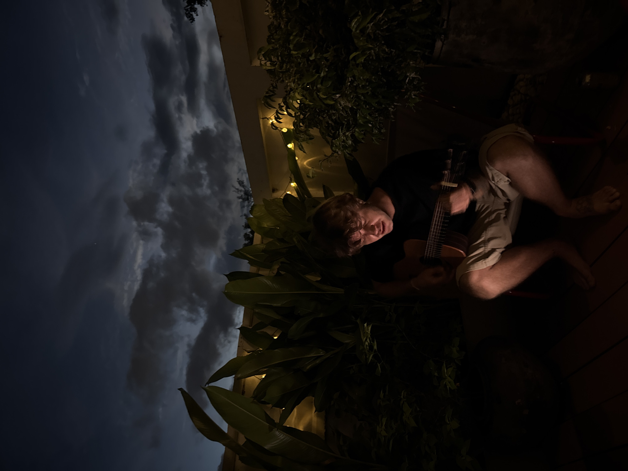 Evening guitar session on a plant-lined deck in Chiang Mai
