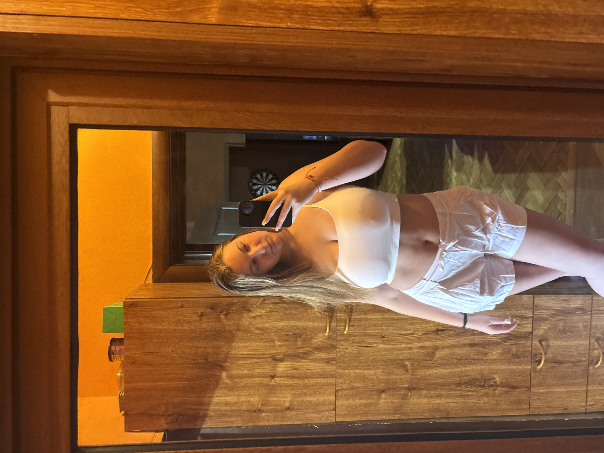Woman takes mirror selfie in yellow-accented room