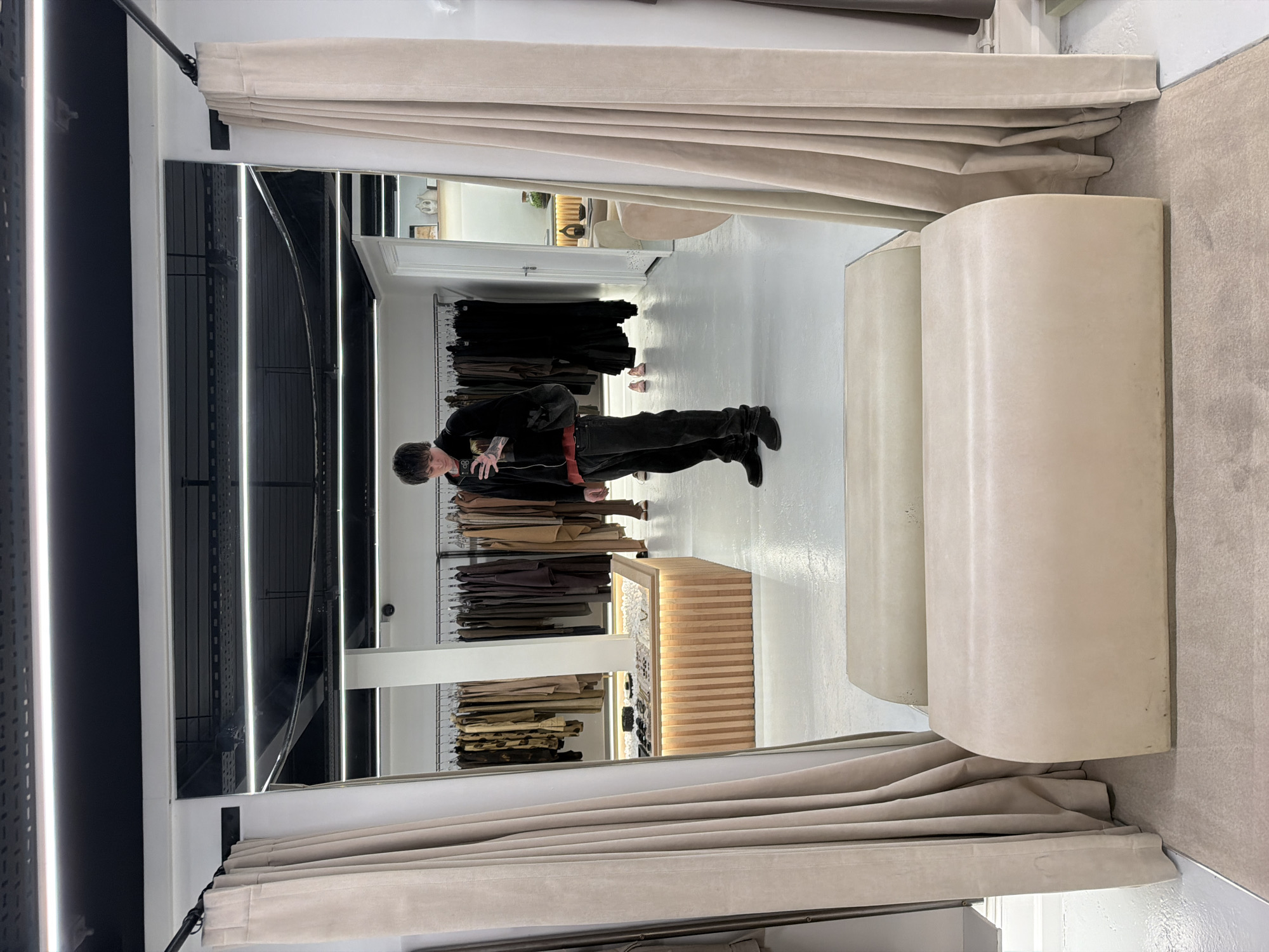 Person tries on dark clothing in London store fitting room