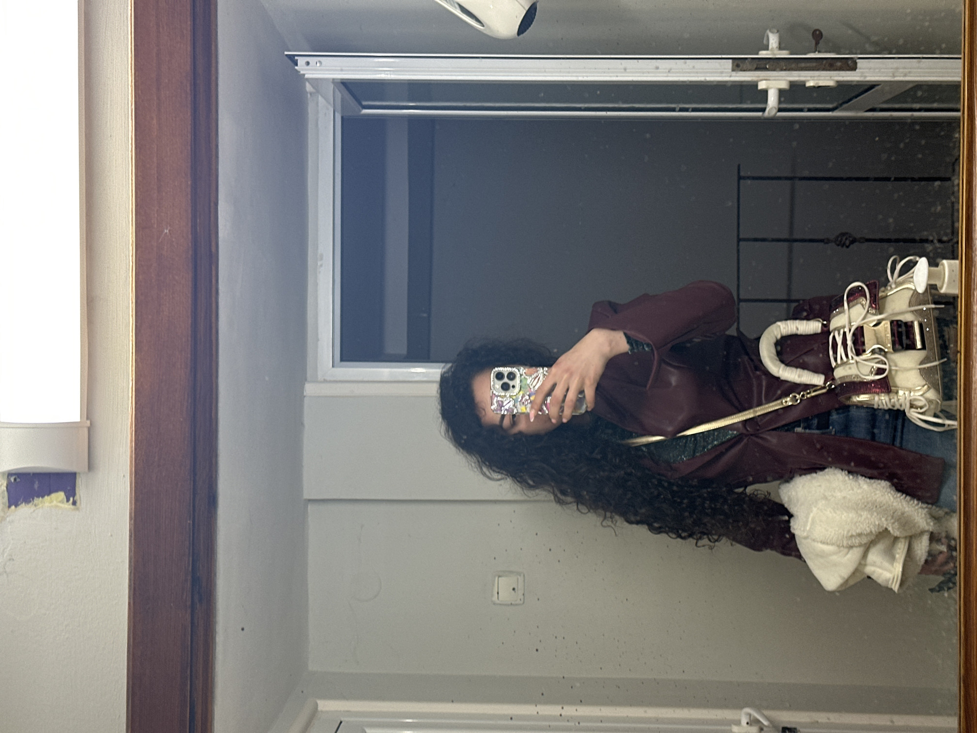 Mirror selfie captured showing person in maroon jacket