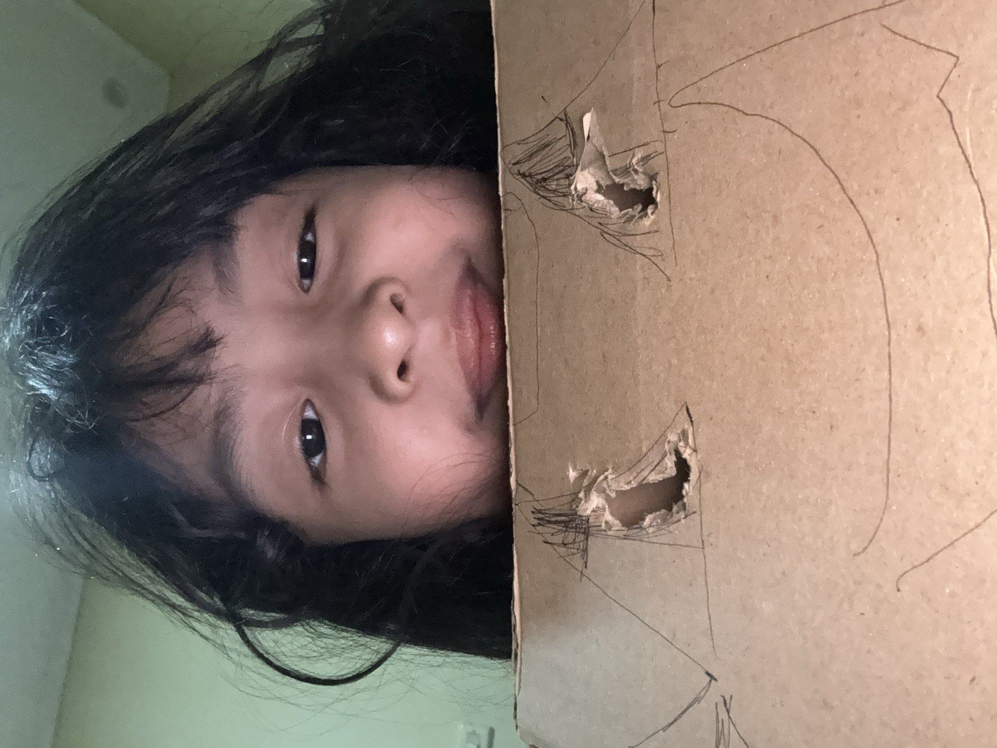Person crafts cardboard mask, rests indoors during afternoon session