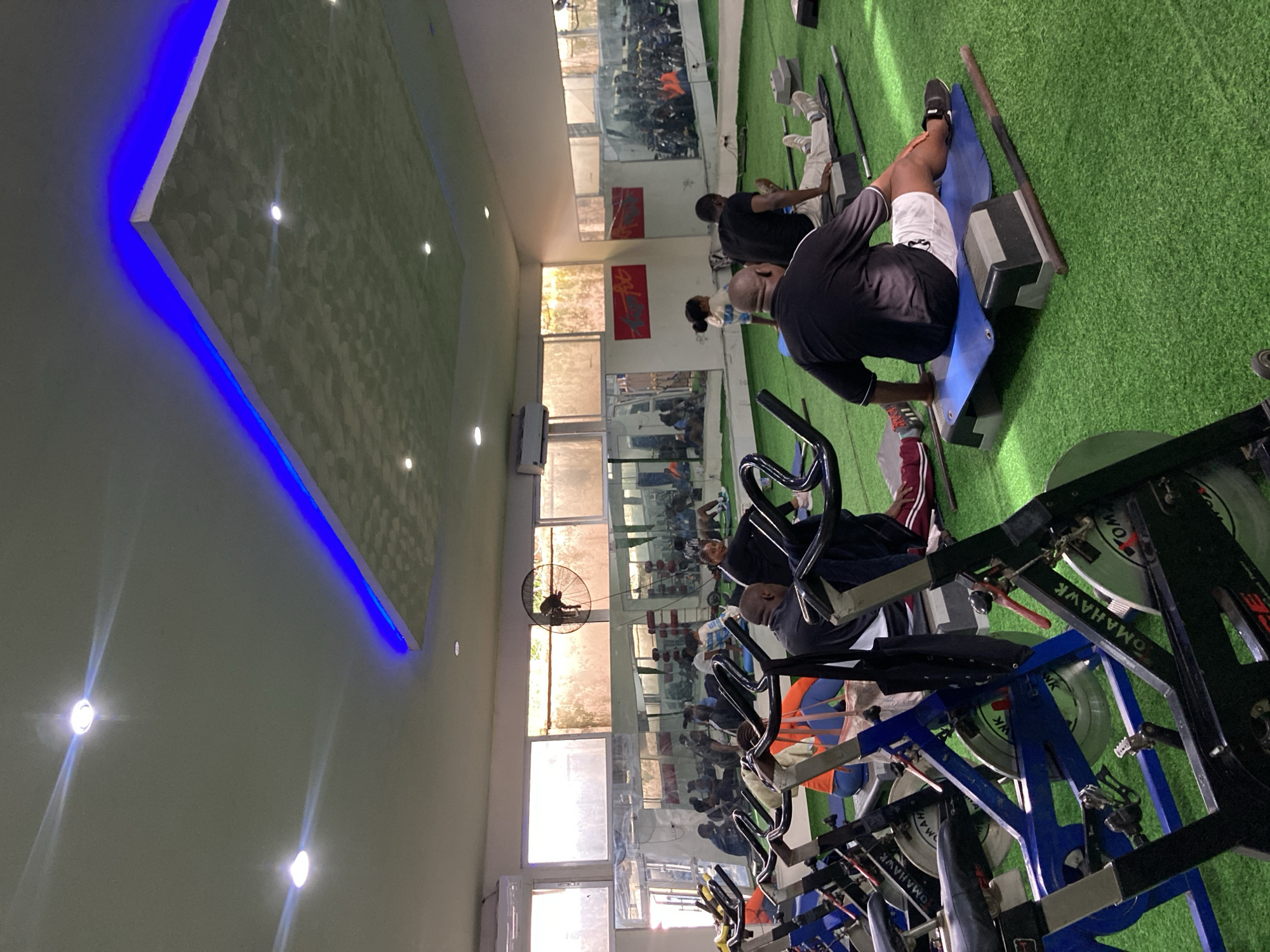 Morning fitness class exercises on green turf in Gwarinpa gym