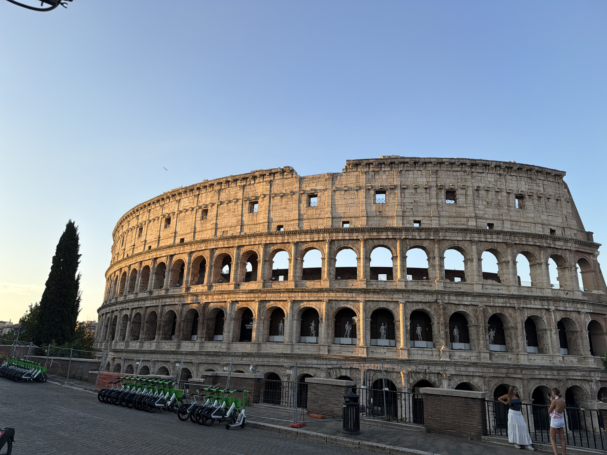 Rome's Colosseum at golden hour, scooters parked out front