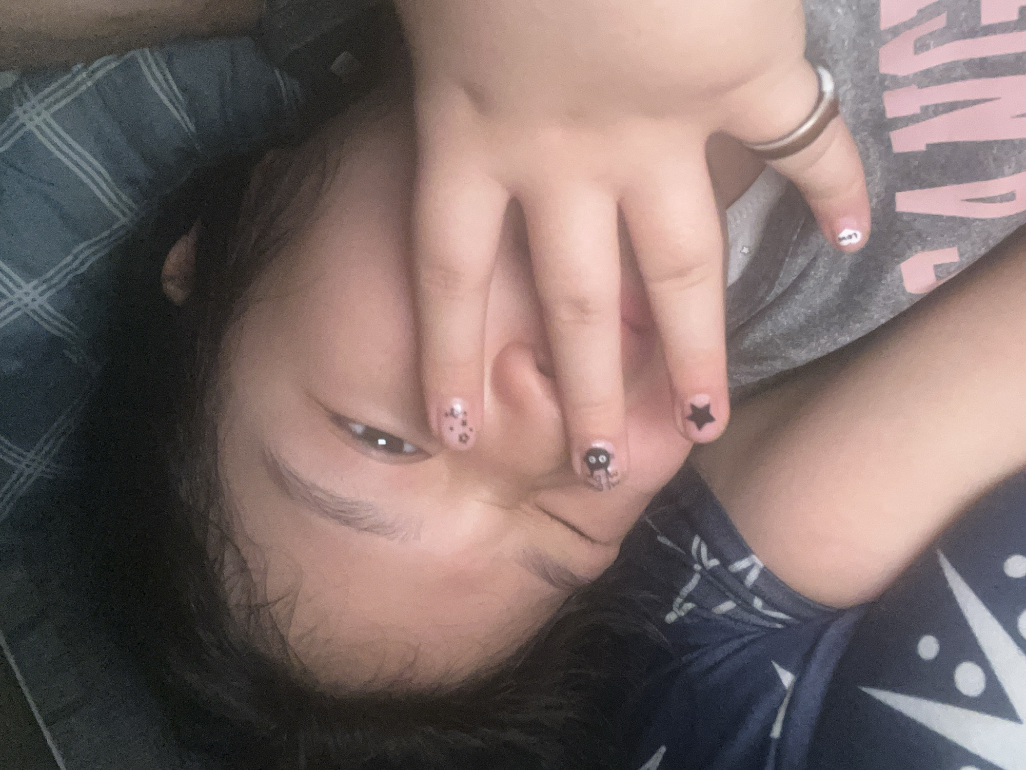 Person with decorated nails rests on plaid bed