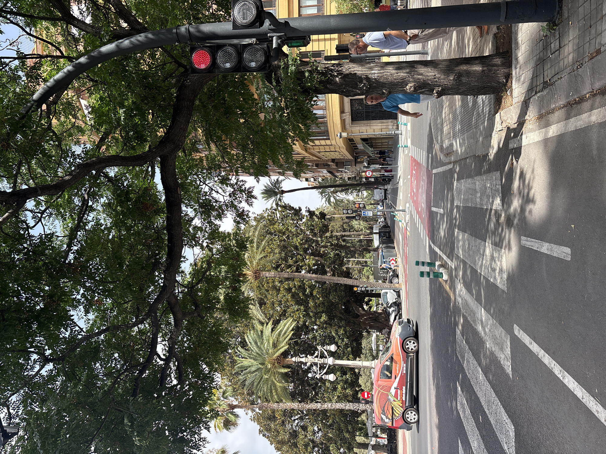 Valencia intersection with bus, van, and pedestrians near green space