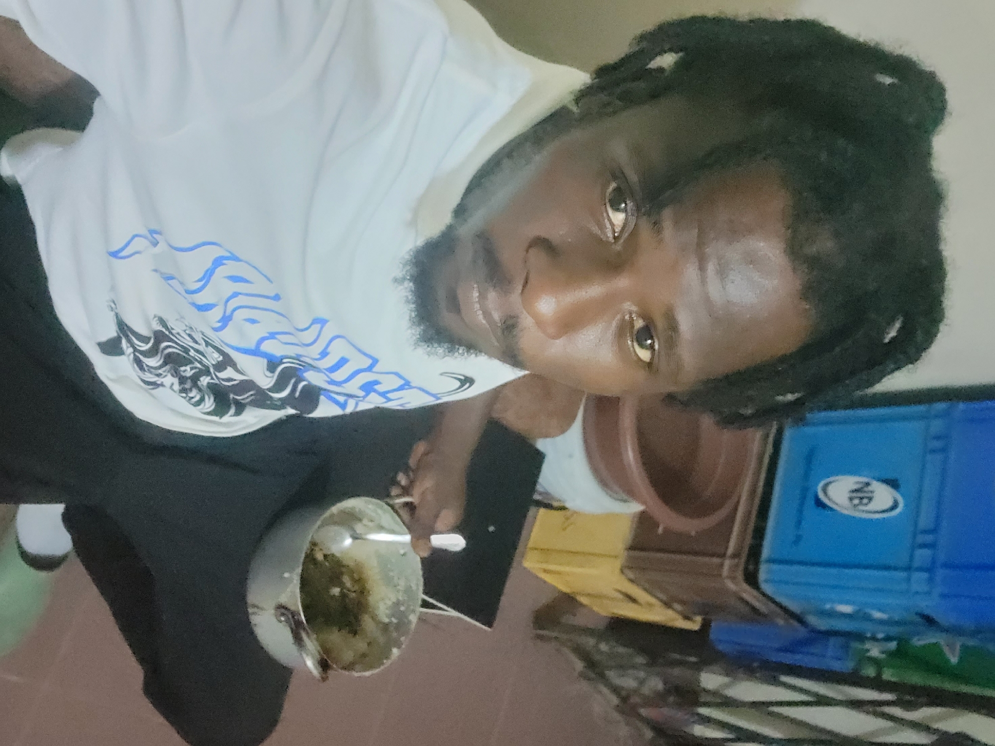 Man eats green vegetables from metal pot in Jos