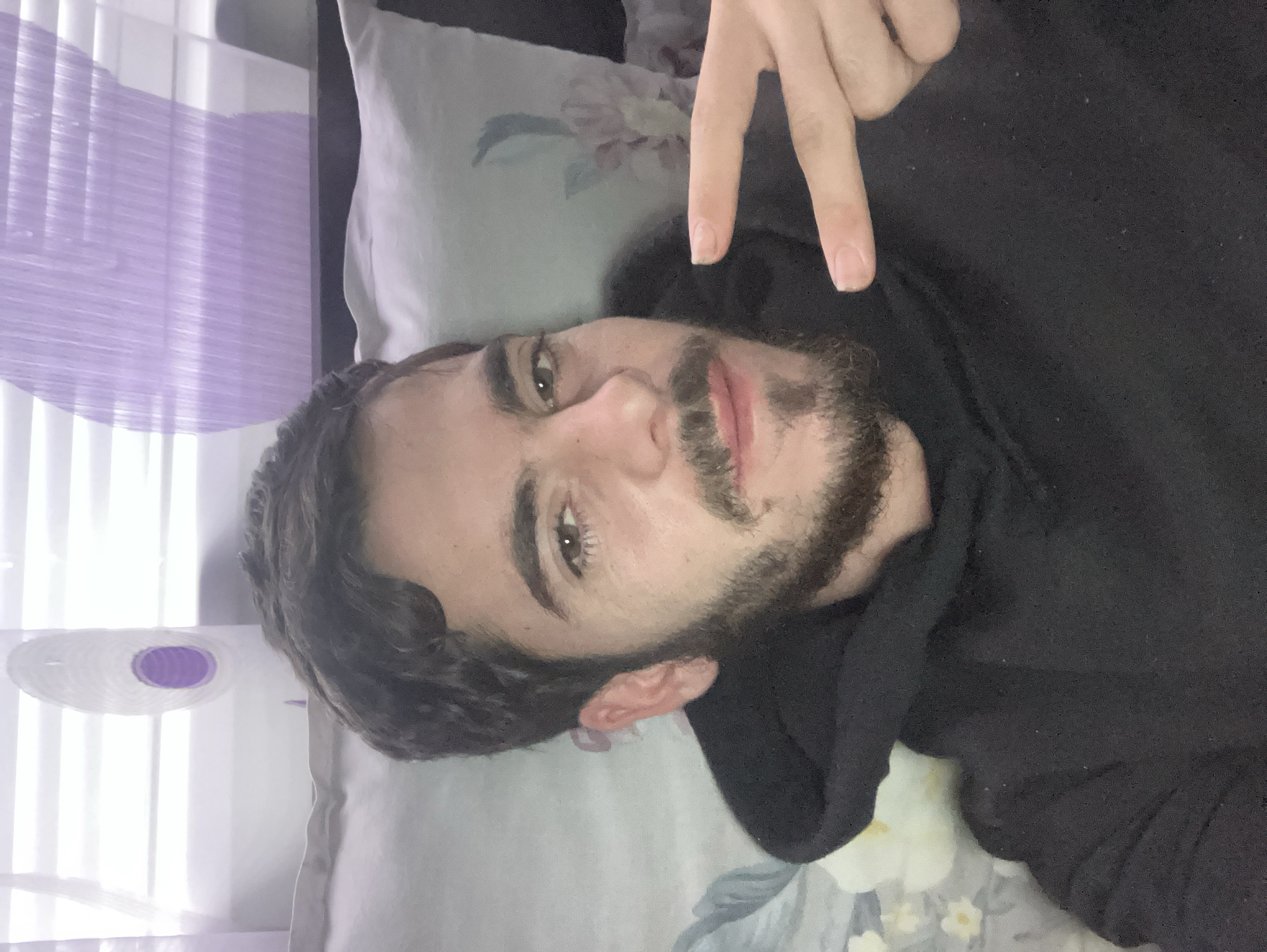 Person makes peace sign while resting on floral pillow