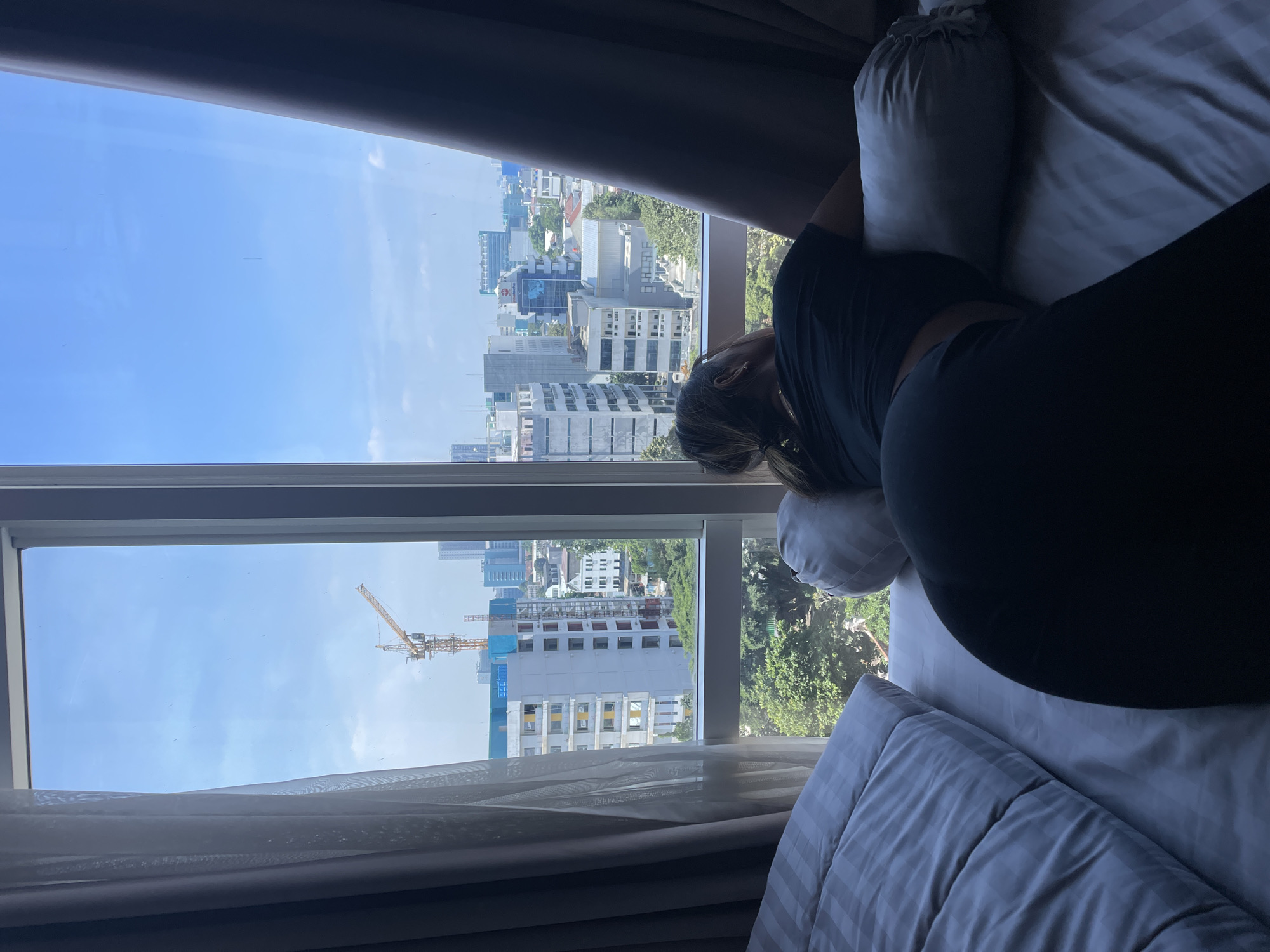 Woman rests by window overlooking Jakarta cityscape
