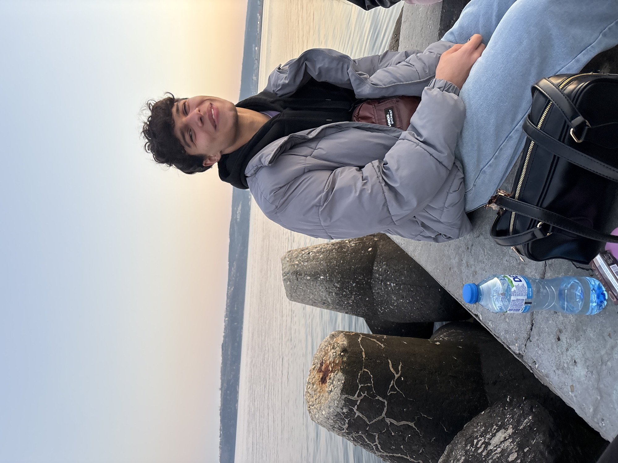 Two people sit on waterfront concrete structure