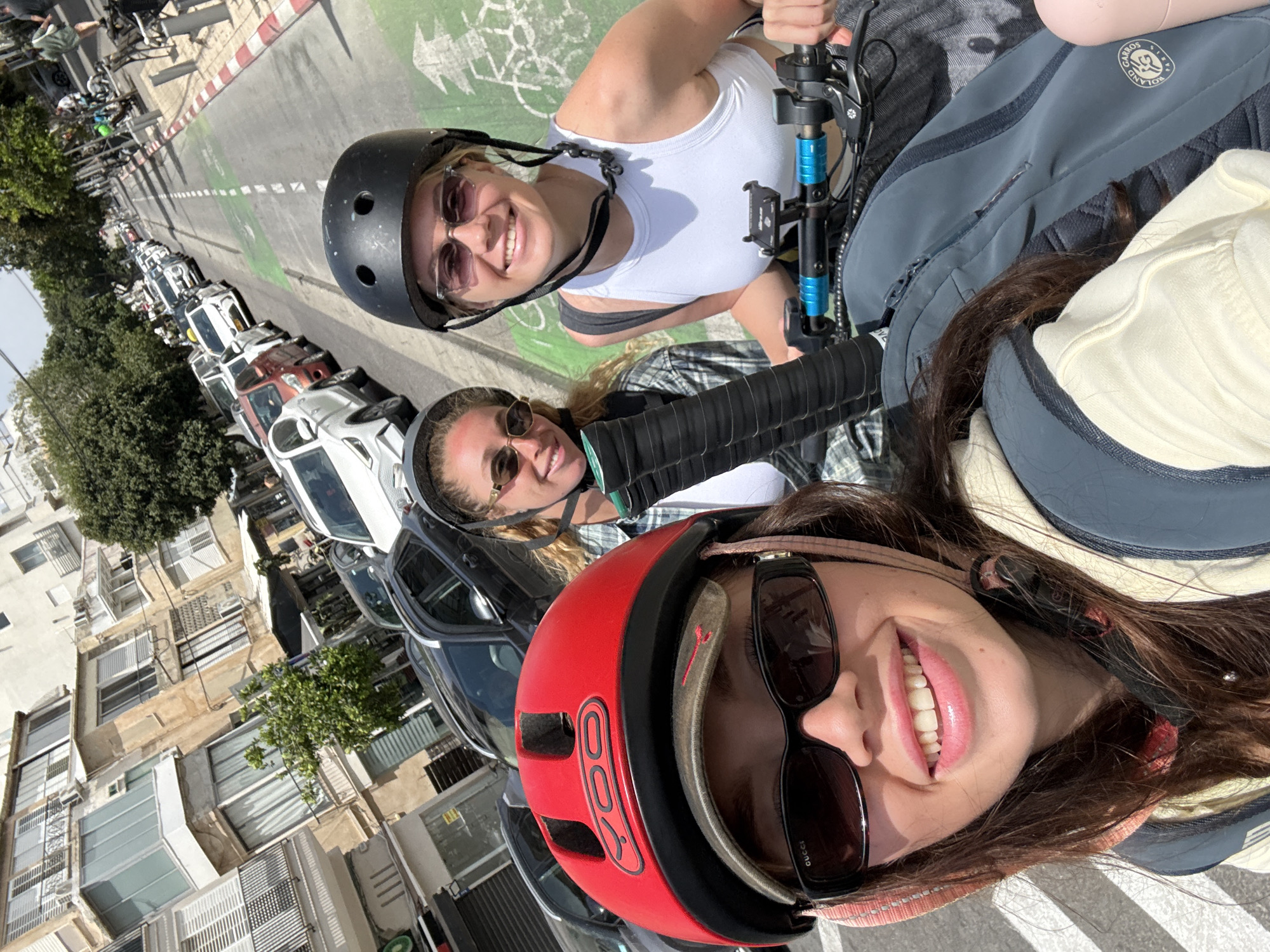 Three women on scooters take selfie in Tel Aviv