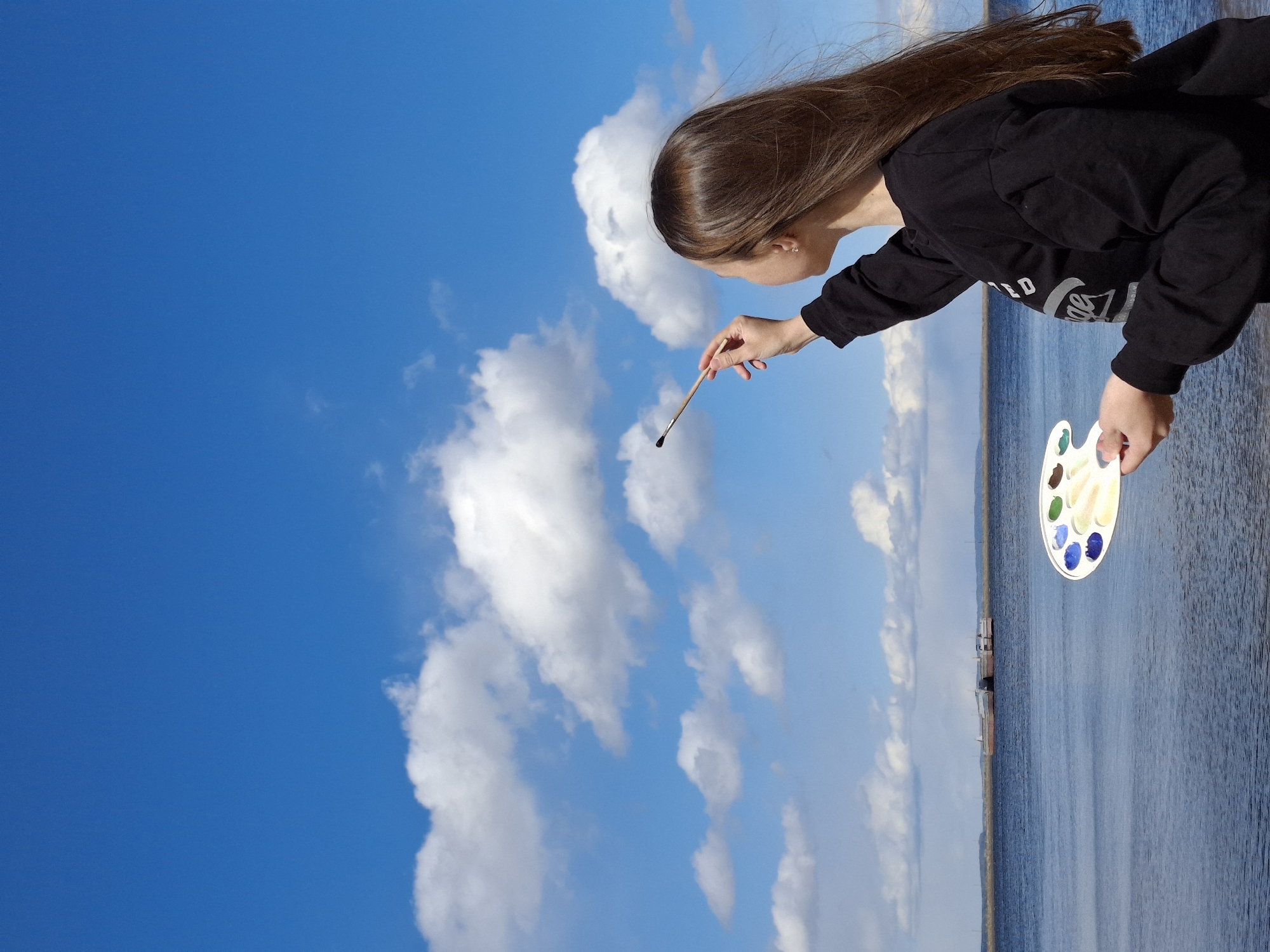 Person photographs artistic poses by waterfront in Chaikovsky Russia