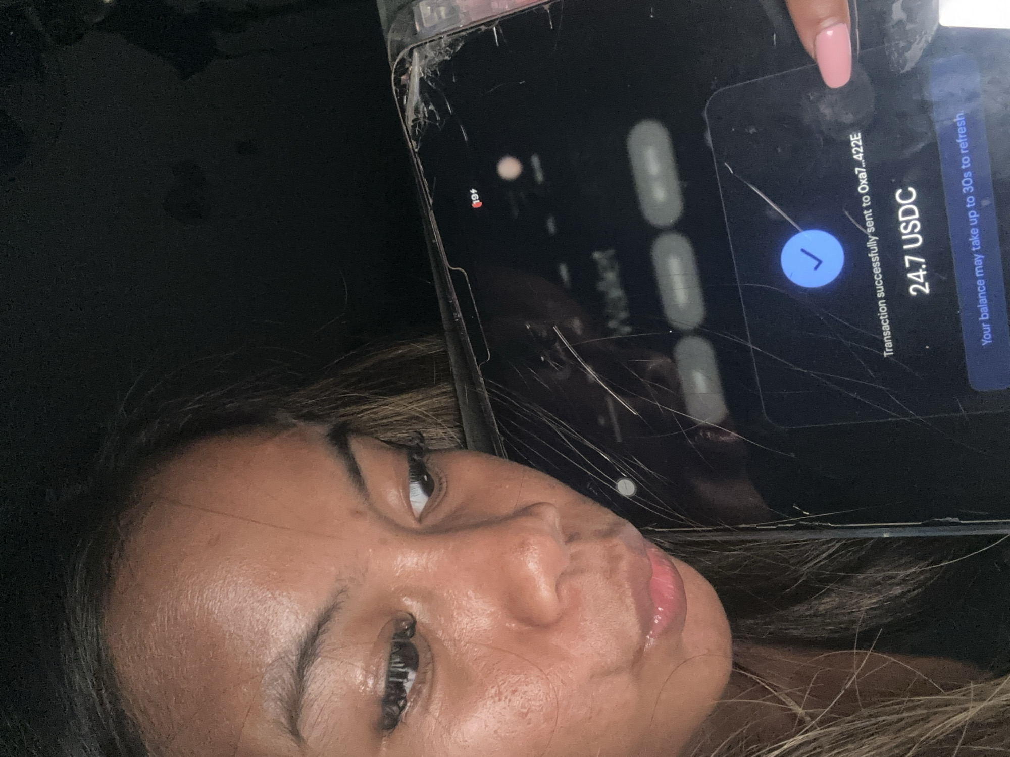 Woman documents crypto transfer on cracked phone in Jakarta