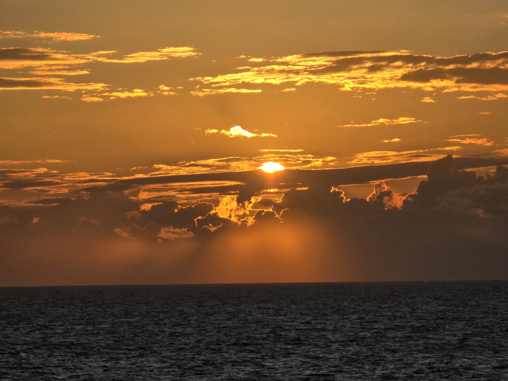 Golden ocean sunset with streaked clouds and warm light