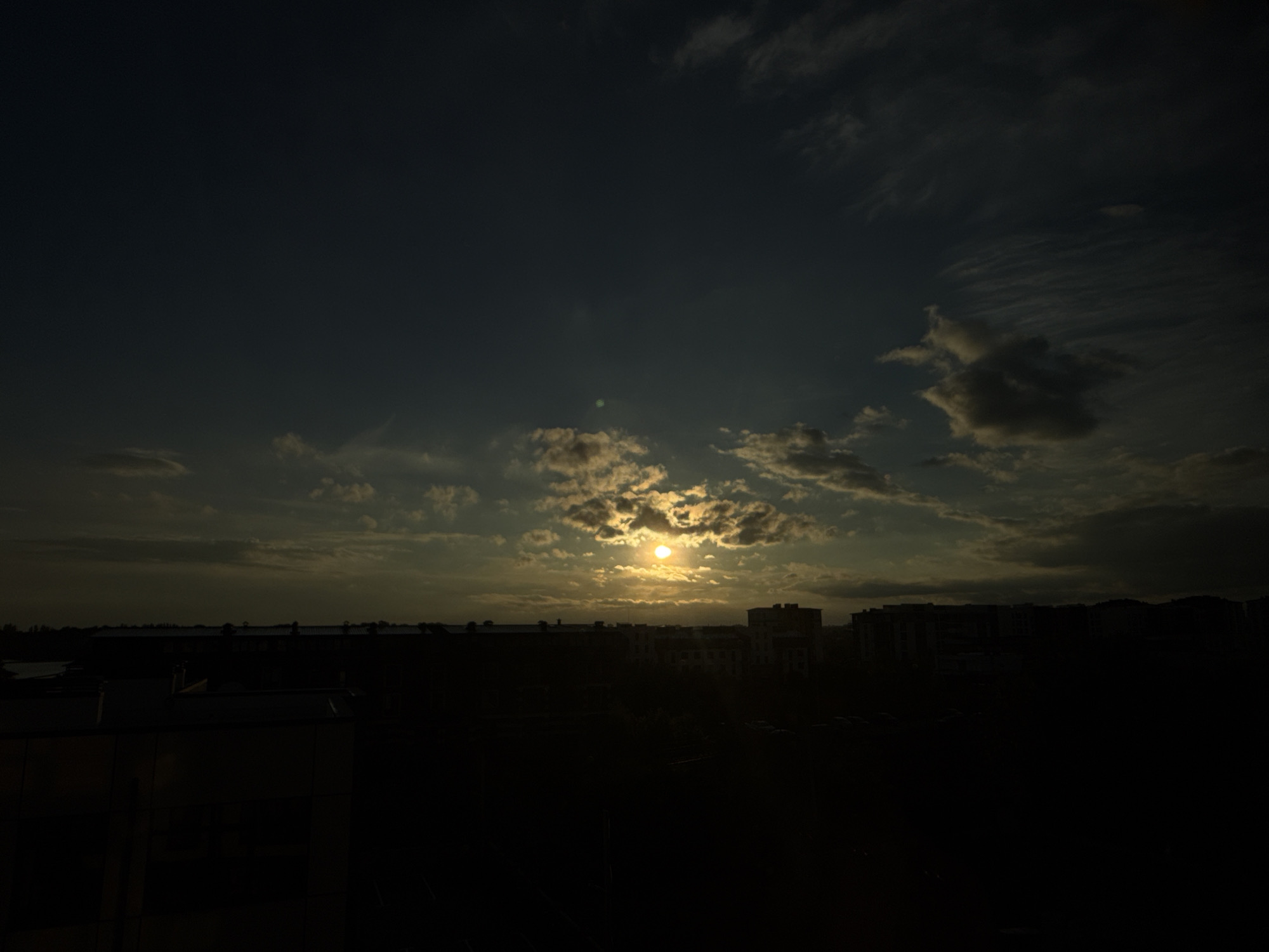 Dramatic sunset with light beams over city skyline